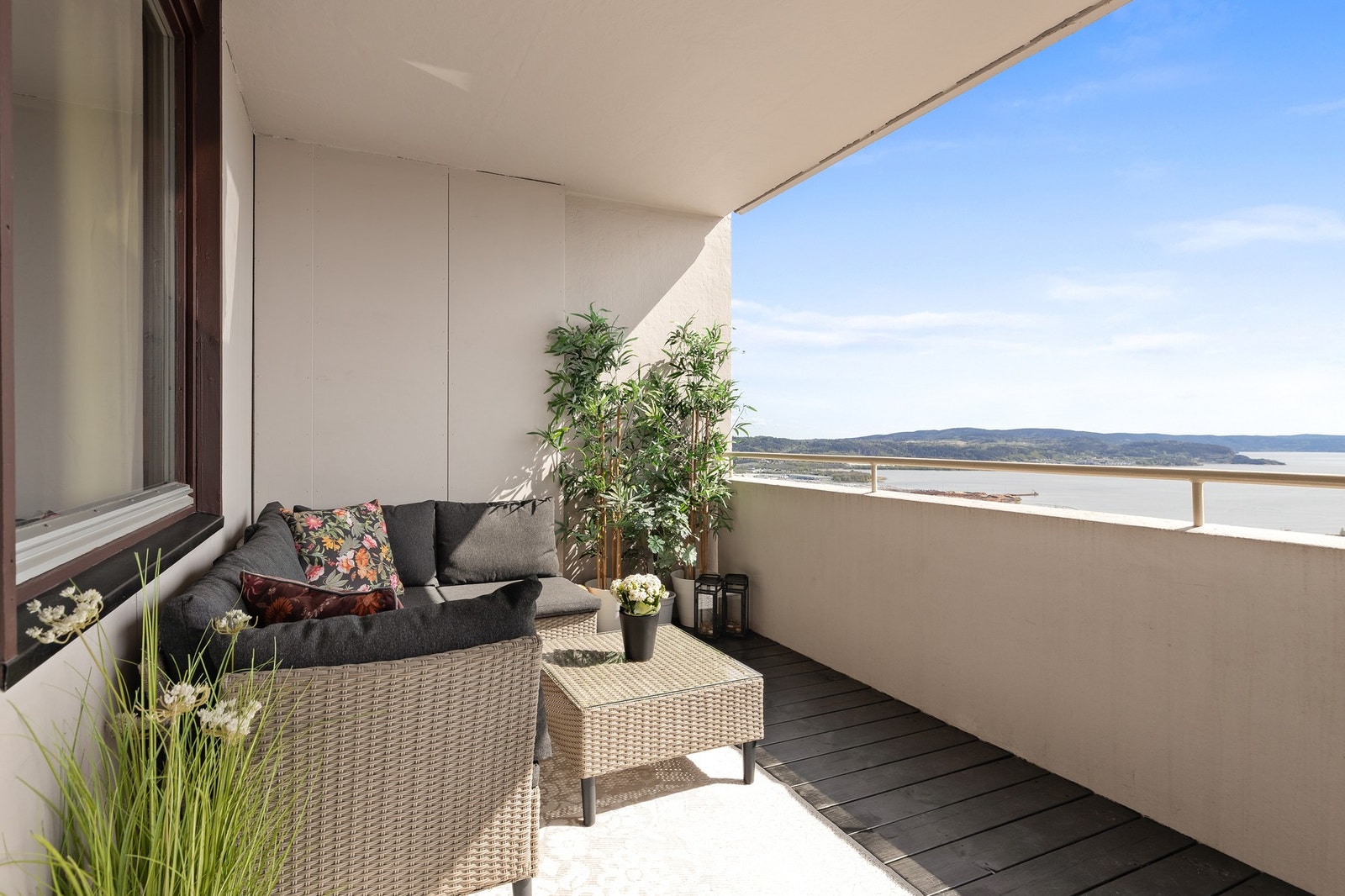 Balkongen har terrassebord på gulv og rekkverk av betong og metall Galleribilde