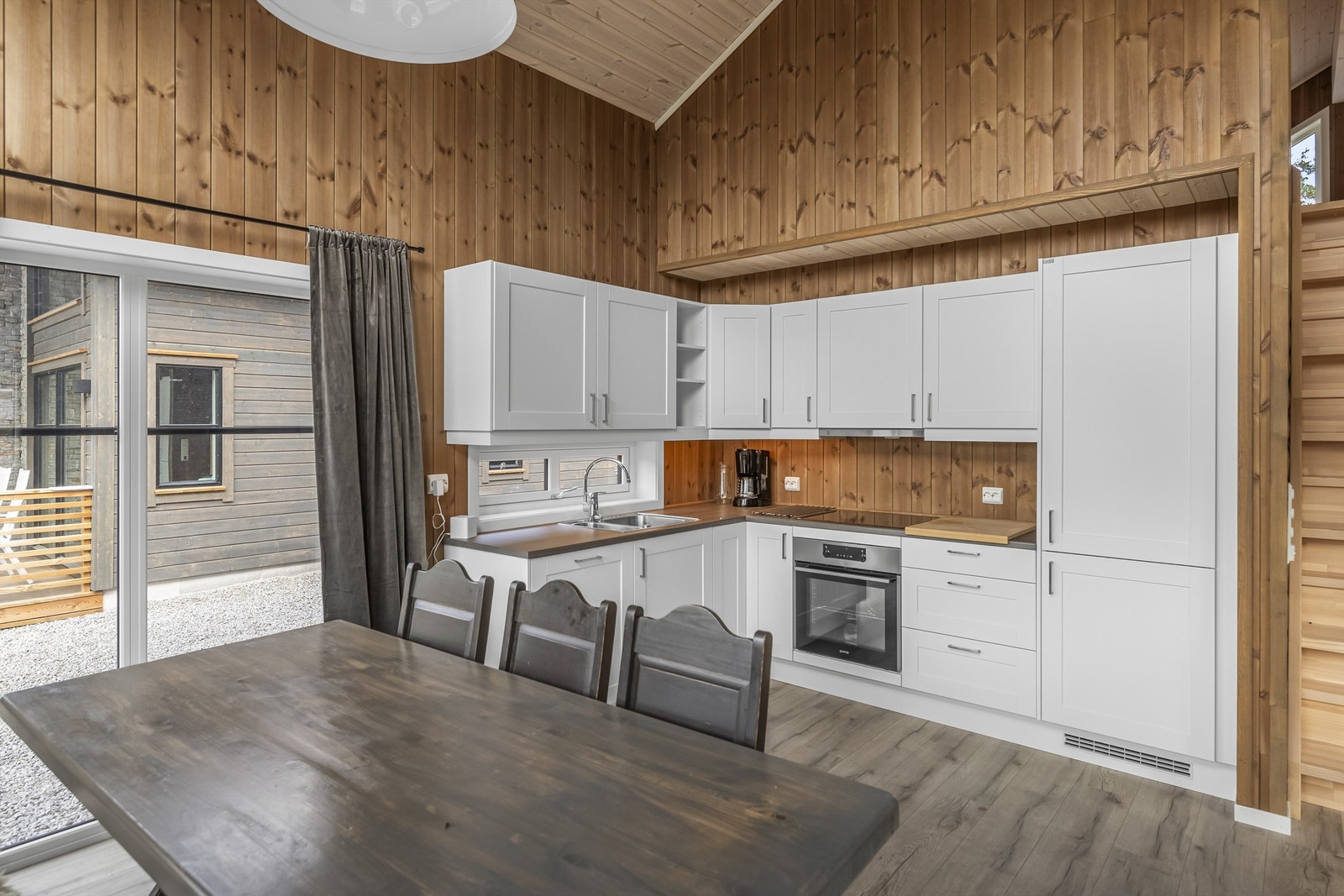 Kjøkkenet er innredet med hvitprofilerte fronter og med integrerte hvitevarer Galleribilde