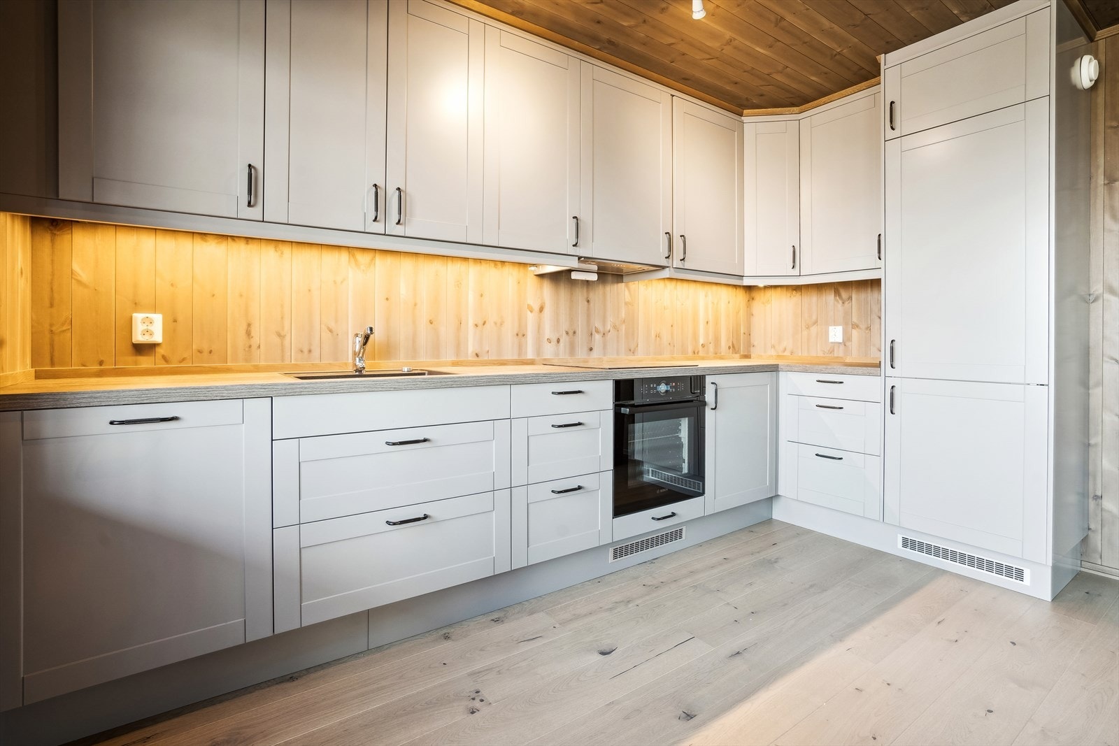 Kjøkkenet har integrerte hvitevarer godt arbeidslys under vegghengte skaper. Galleribilde