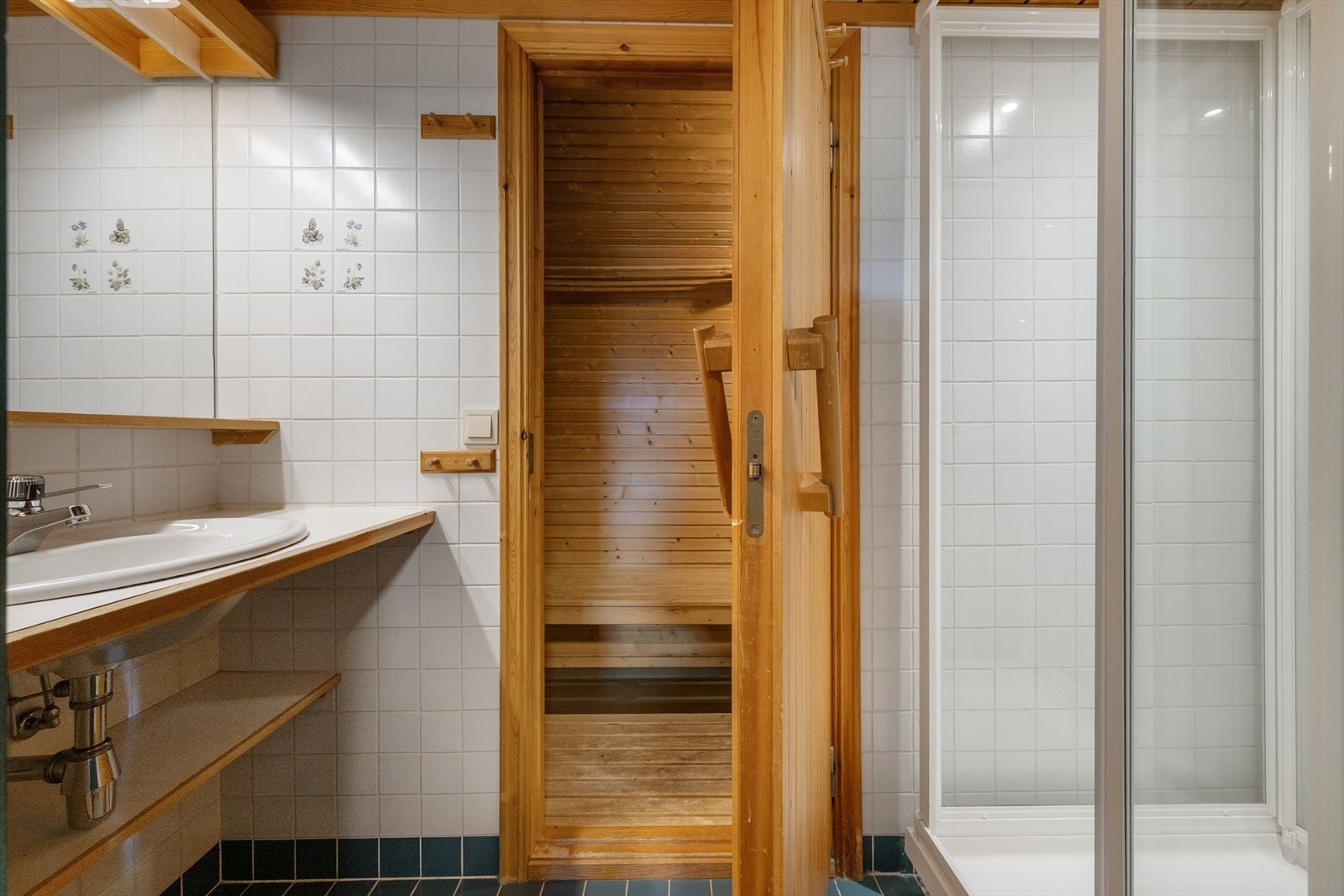 Badet har flislagte overflater og varme i gulv, og er enkelt innredet med servant, speil og dusjkabinett. Galleribilde