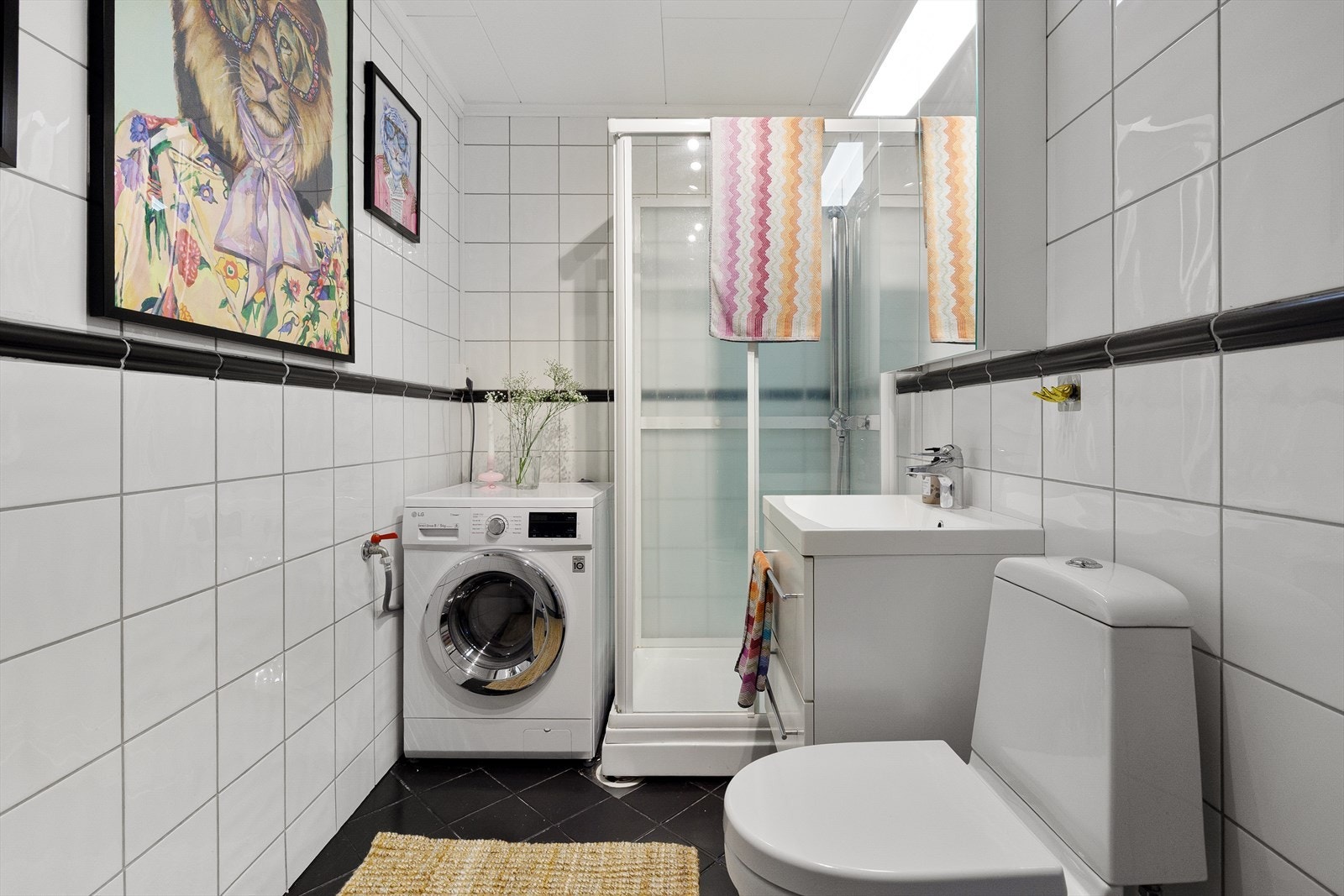 Flislagt bad med varmekabler, servant med innredning, speilskap, dusjkabinett og opplegg for vaskemaskin. Galleribilde