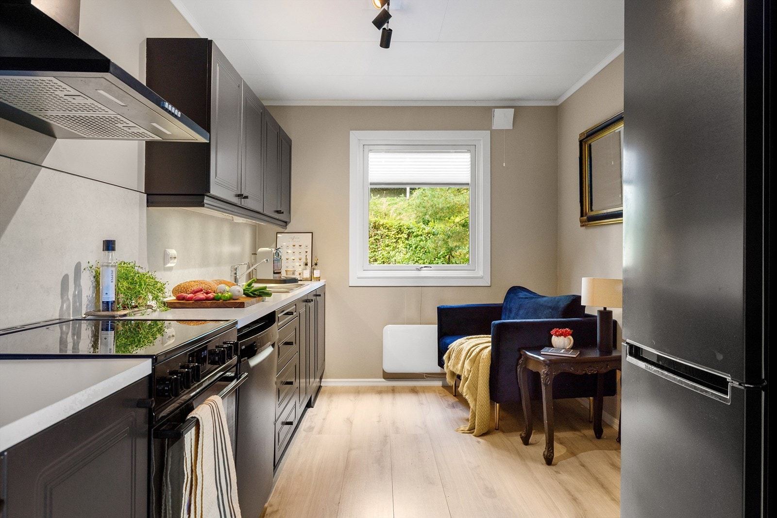 Kjøkken med profilerte heltre fronter som er malt i nyere tid, lys benkeplate og frittstående hvitevarer. Praktisk plassert i forlengelsen av stuen og adskilt med skyvedør. Galleribilde