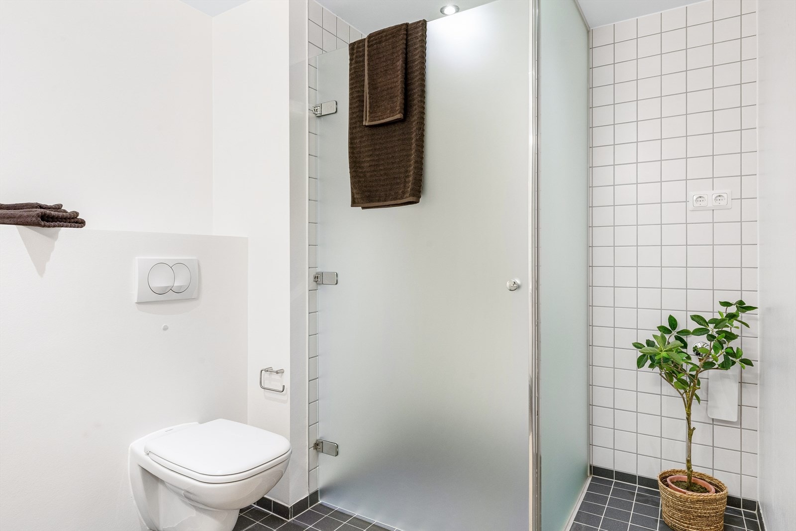 Baderom med fliser, dusjhjørne og opplegg for vaskemaskin. Galleribilde