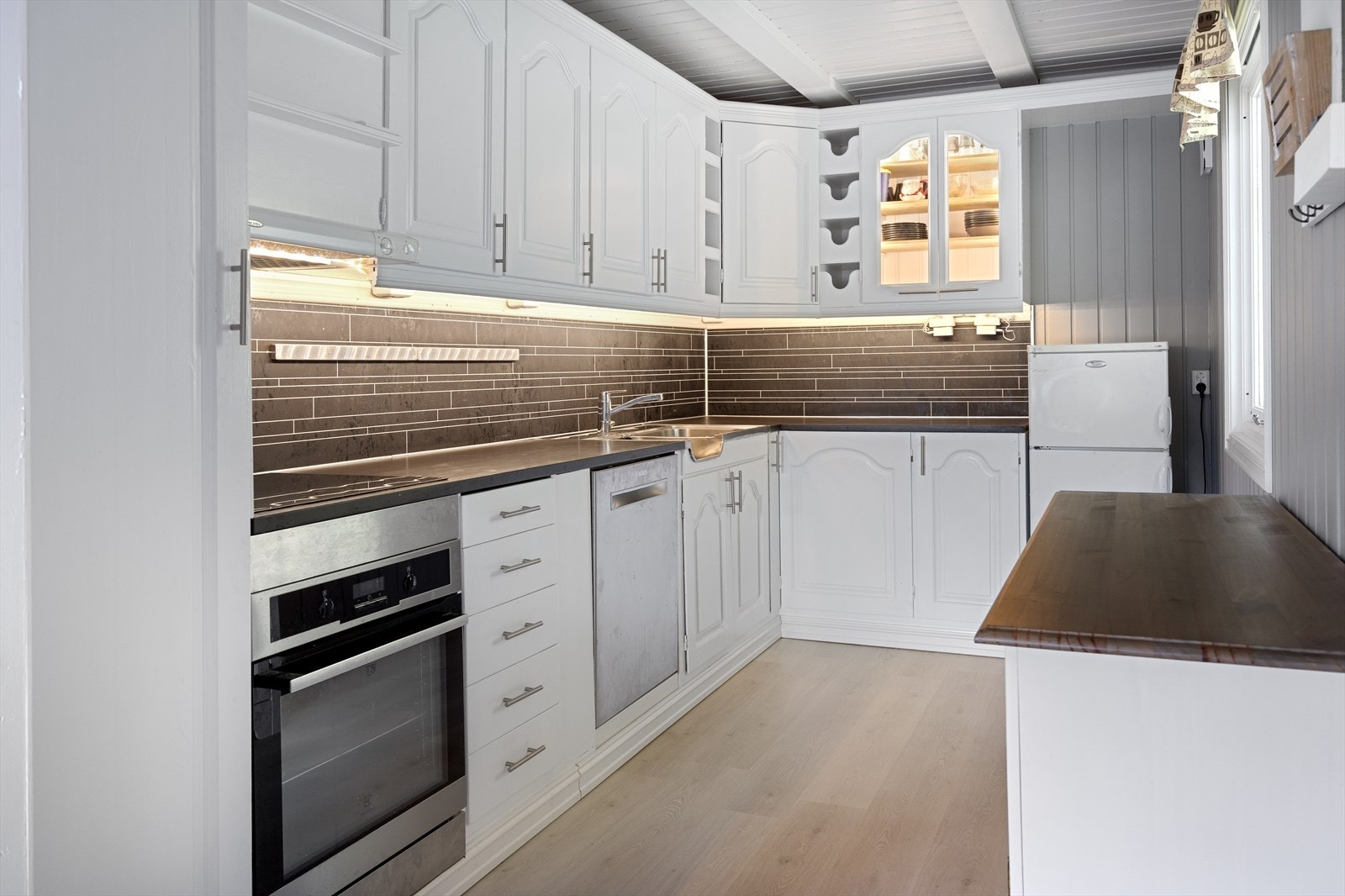 Lyst og pent kjøkken som har innredning med profilerte fronter. Benkeplaten er av laminat. Galleribilde