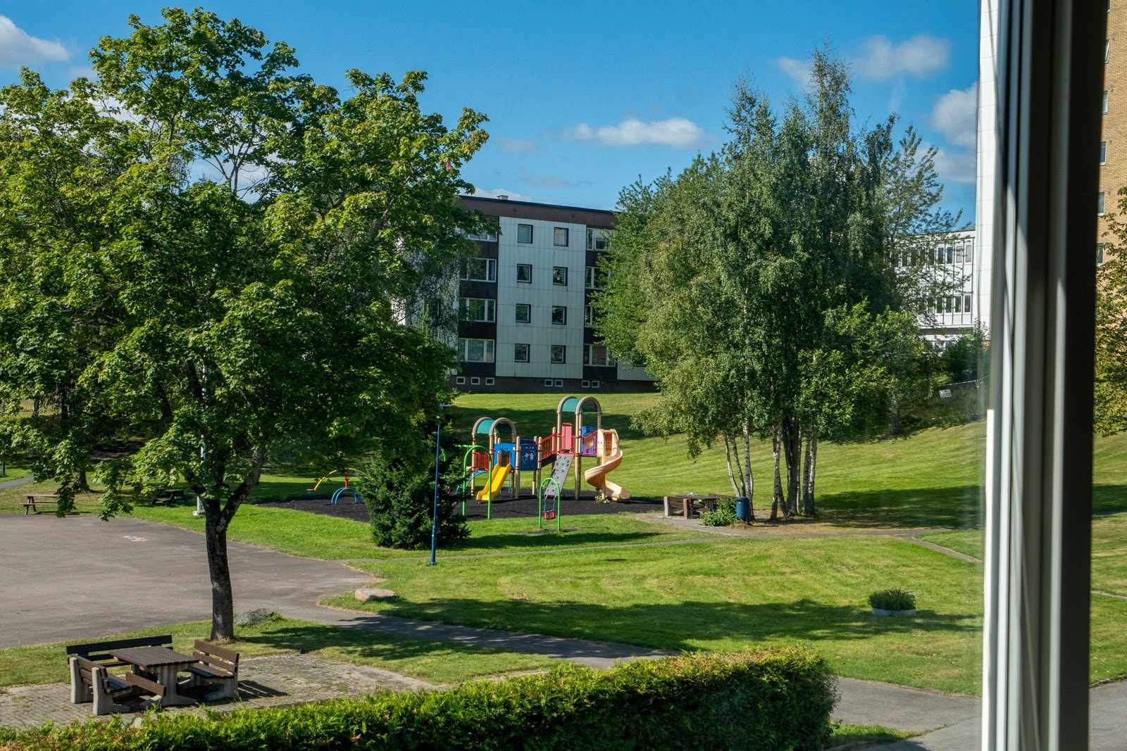 Utsikt fra leiligheten til velstelt borettslagsområde med grøntarealer og lekeplasser. Galleribilde