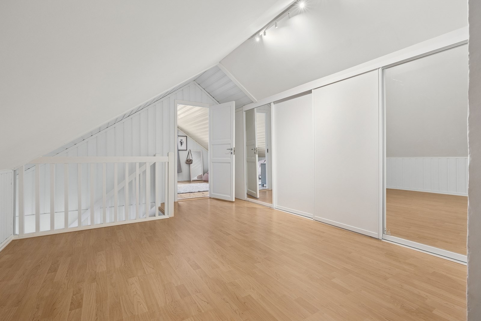 Ny hvitmalt trapp med eiketrinn opp til loftsetasjen i 2018. Trappen fører opp til en stor gang som har vært benyttet som en "loftstue". Det er ikke takvinduer / naturlig lysinnslipp til dette rommet. Det er stor skyvedørsgarderobe, mot knevegg. Galleribilde