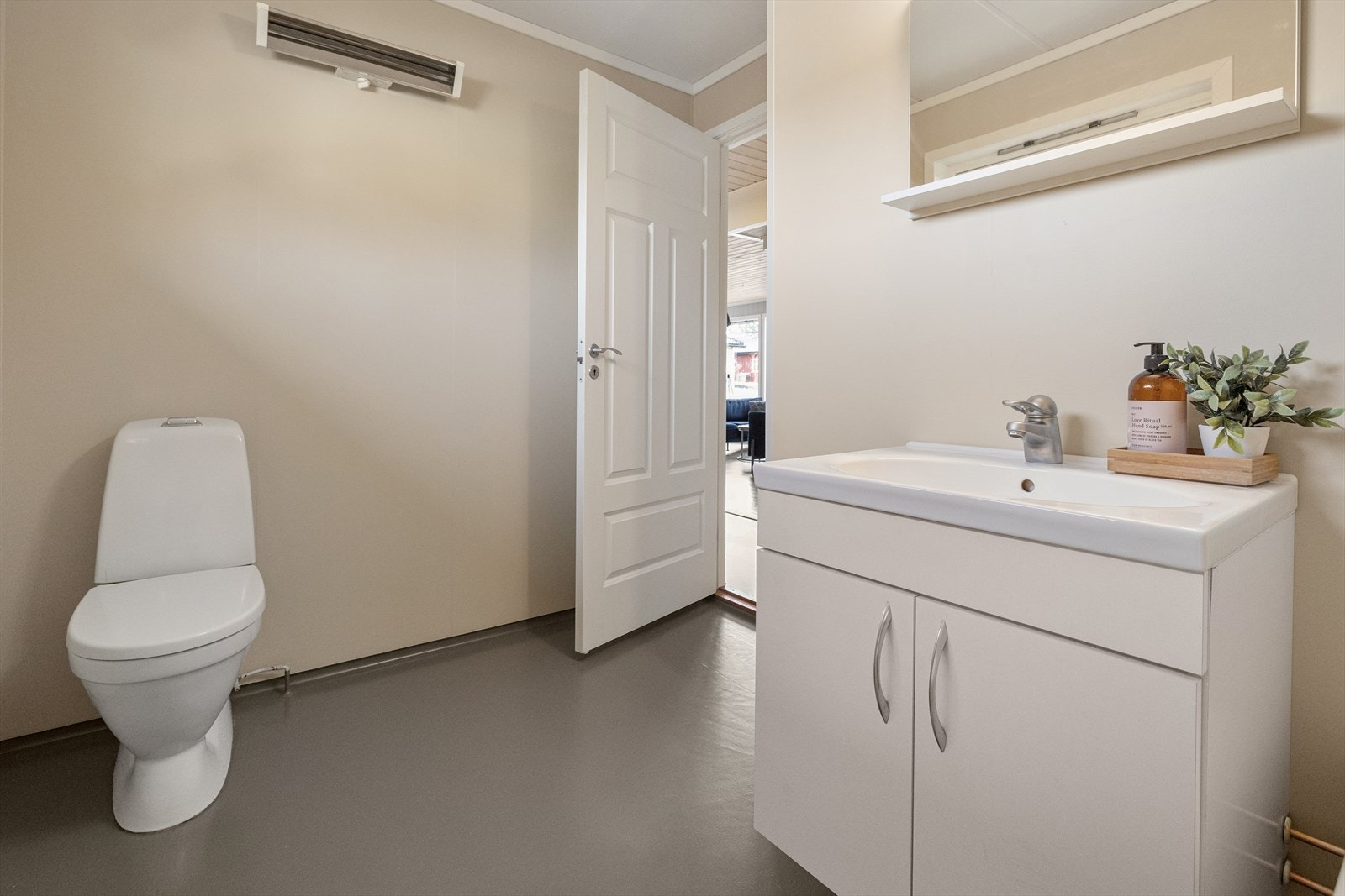 Servant med tilhørende underskap og et gulvstående toalett. Badet er av god størrelse. Det er separat vaskerom. Galleribilde