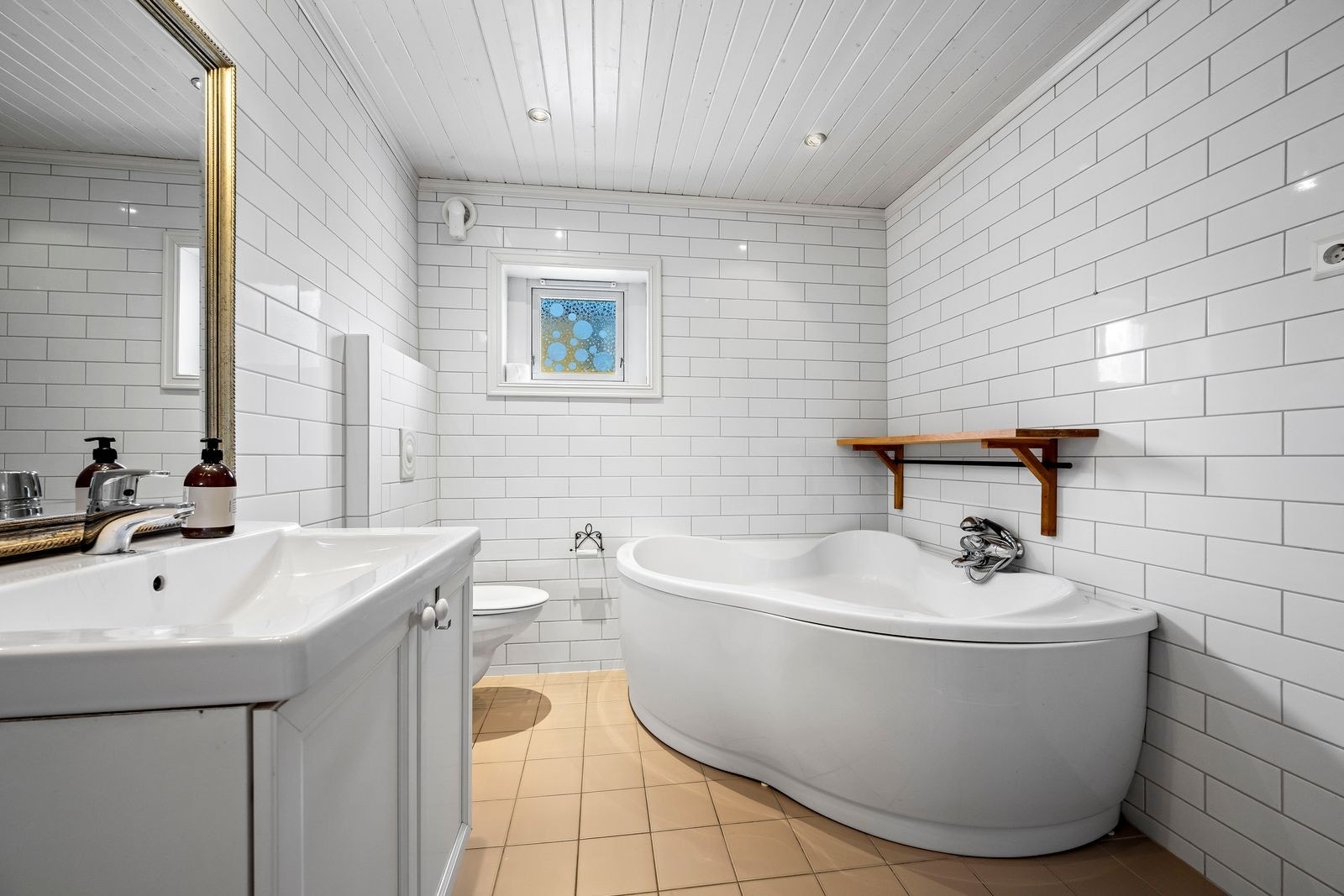 Rommet er innredet med toalett, badekar, dusjnisje, baderomsinnredning med vask og opplegg til vaskemaskin Galleribilde