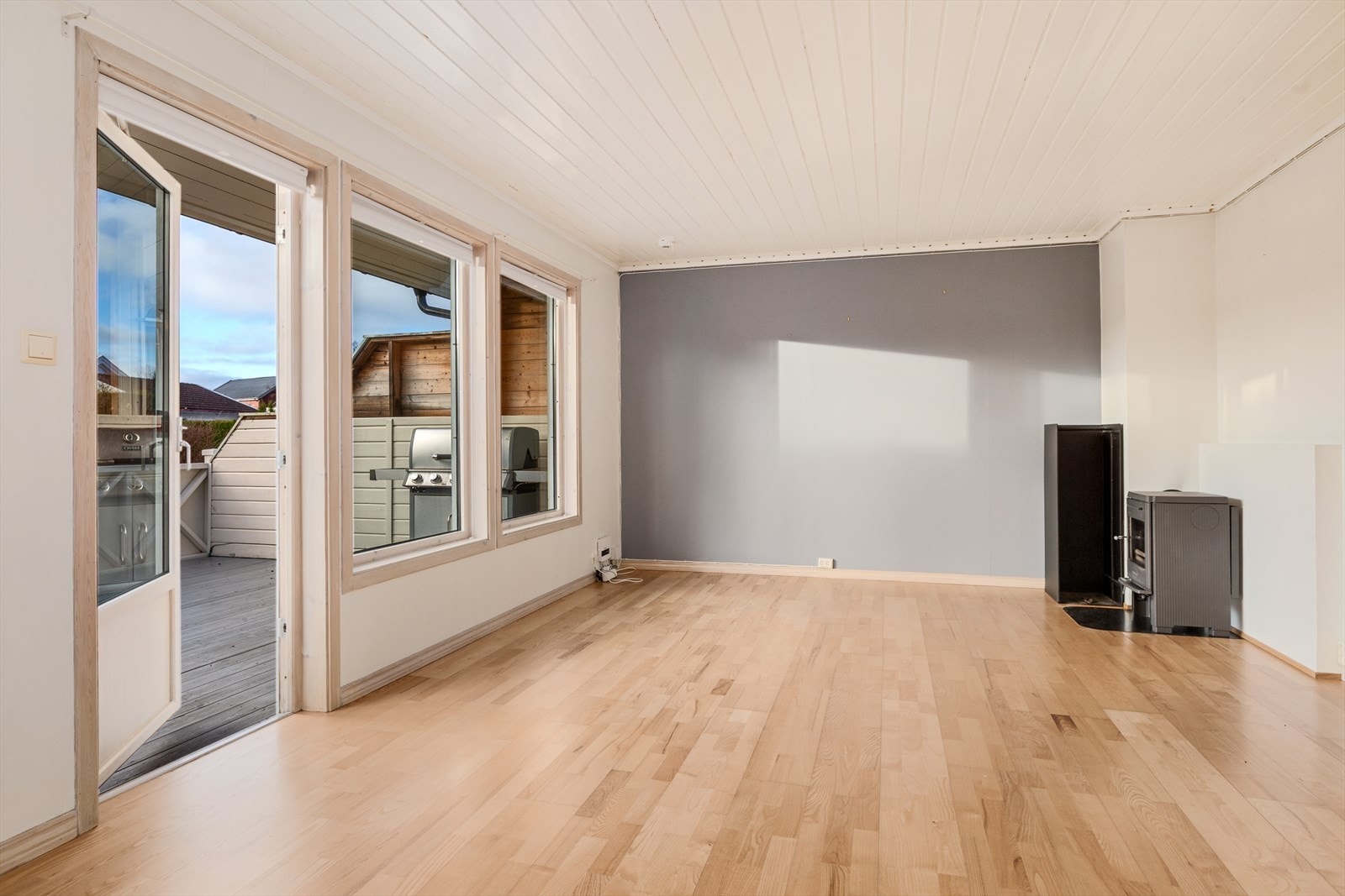 Stue med parkettgulv og varmekabler, malt tapet på vegger og vedovn. Utgang til delvis overbygget sydvendt terrasse Galleribilde