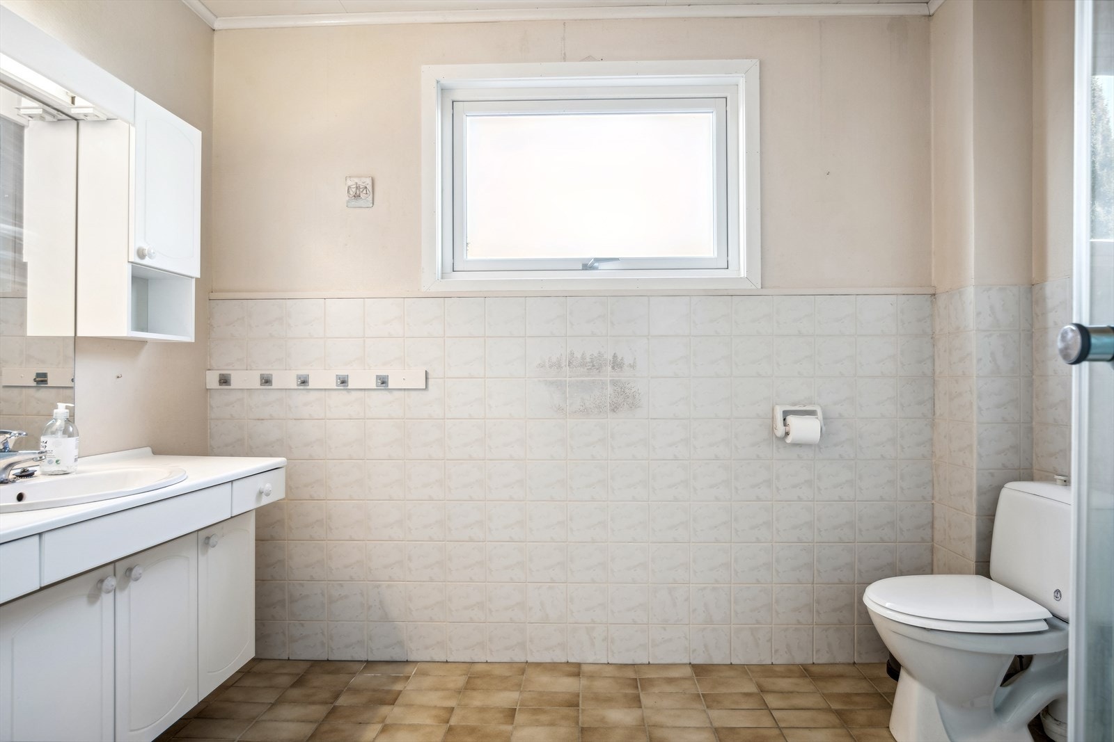 Romslig bad med masse potensiale. Badet har flislagt gulv med varmekabler, samt fliser og strietapet på vegger. Galleribilde