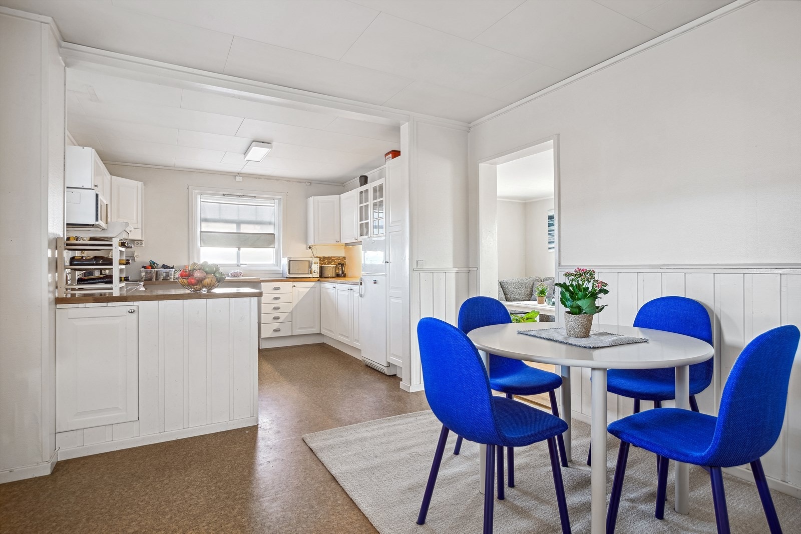 Kjøkkeninnredning i lyse og profilerte fronter, benkeplate i heltre og fliser mellom benk og overskaper. Galleribilde