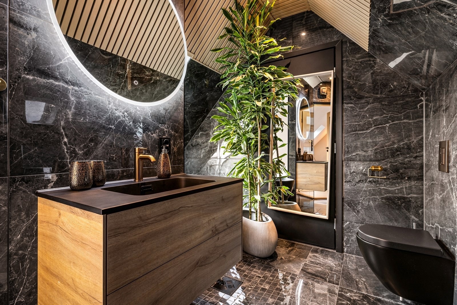 Stilrent bad med vegghengt toalett, servant med skuffer og speil med belysning. Galleribilde