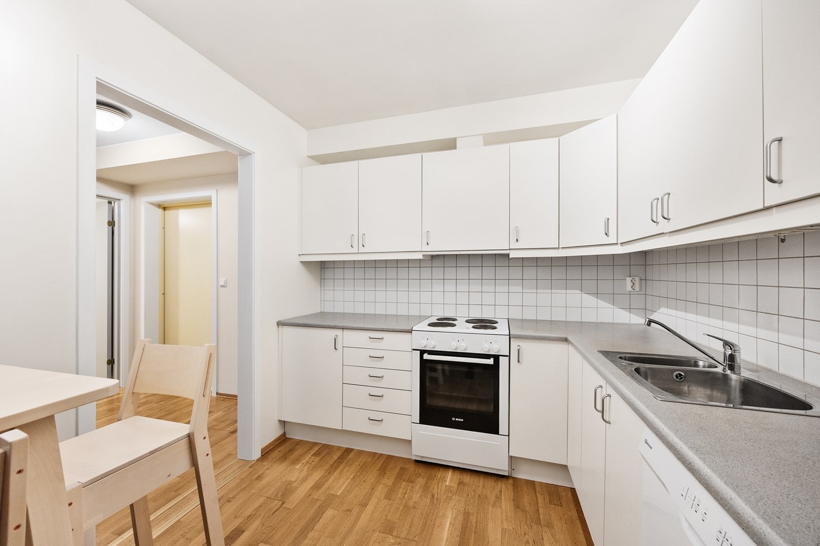 Kjøkkeninnredningen har hvite, glatte fronter, laminatbenkeplate og opplegg for oppvaskmaskin. Galleribilde