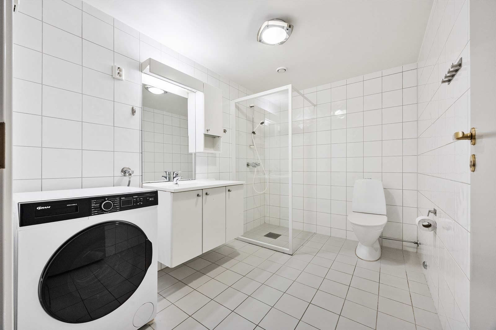 Romslig, helfliset bad med servantinnredning, speilskap og toalett. Galleribilde