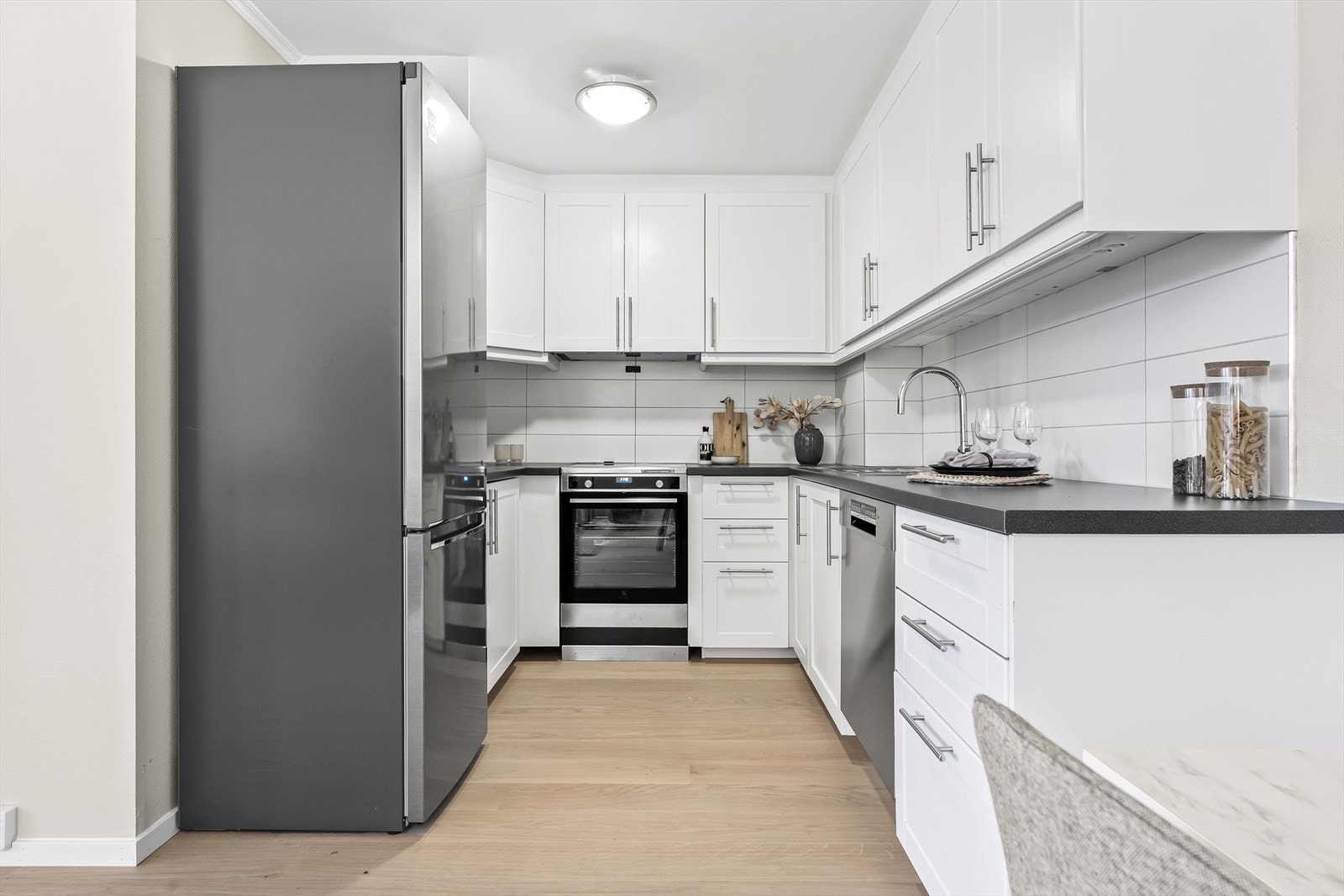 Hvite, profilerte fronter og benkeplate med nedfelt vask. Galleribilde