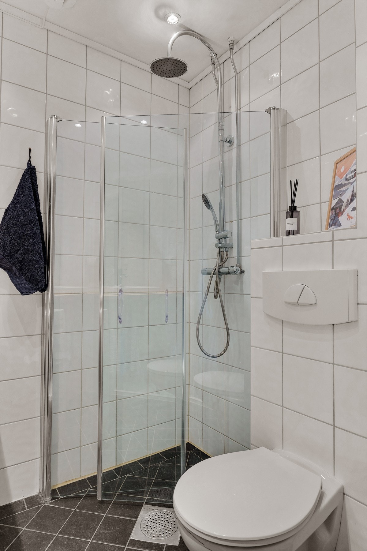 Dusjhjørne med regnfallsdusj og innfellbare dusjdører og vegghengt toalett. Galleribilde