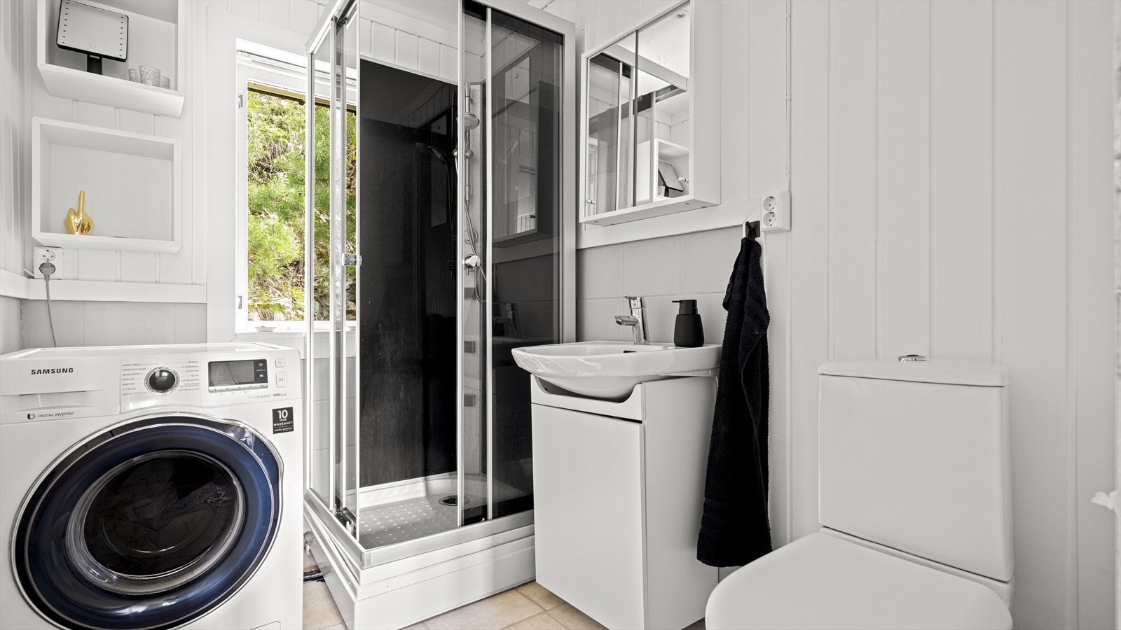 Badet har flislagt gulv, opplegg for vaskemaskin og dusjkabinett. Galleribilde