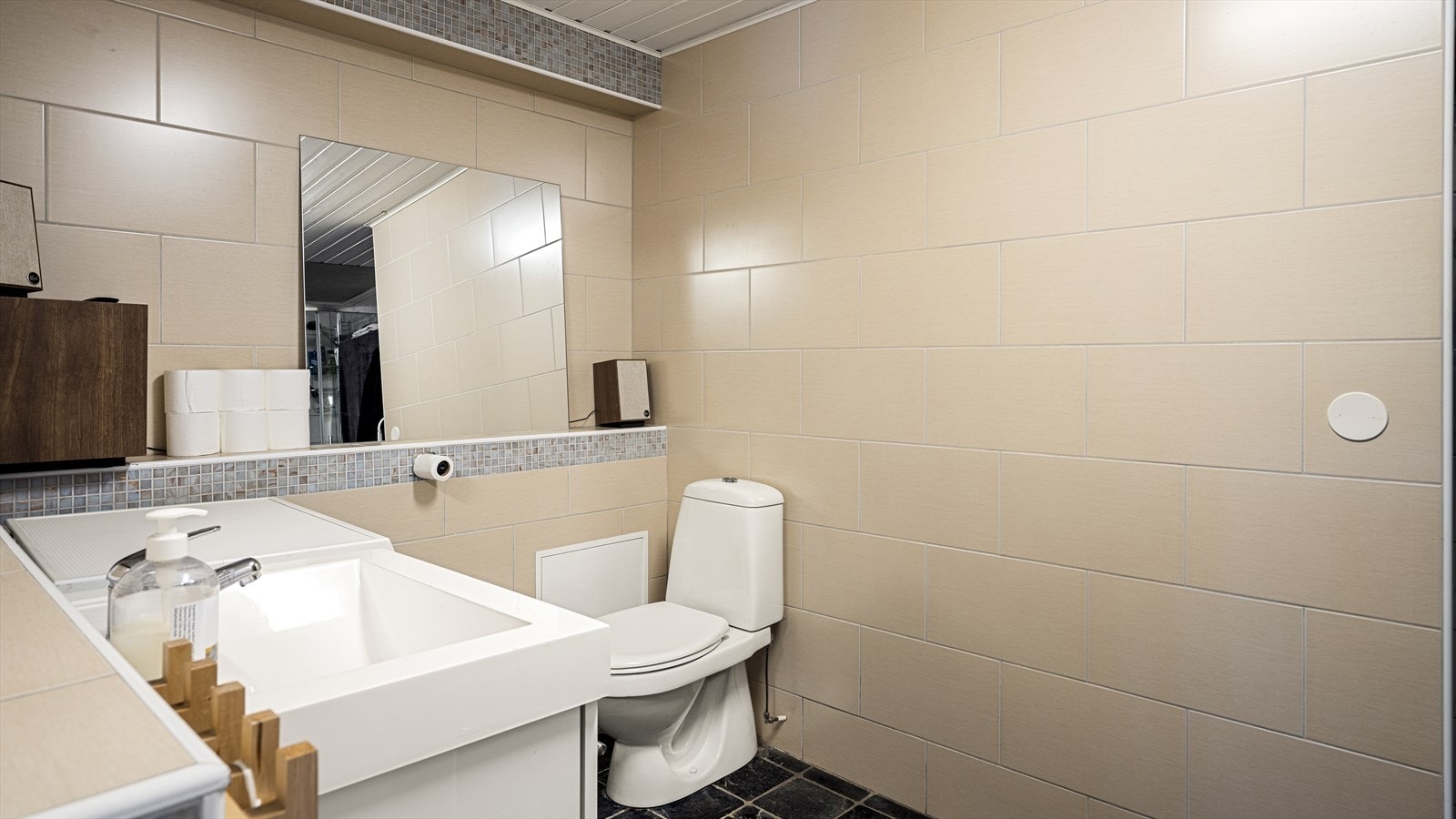 Flislagt bad med servant, toalett, dusjkabinett og opplegg for vaskemaskin. Galleribilde