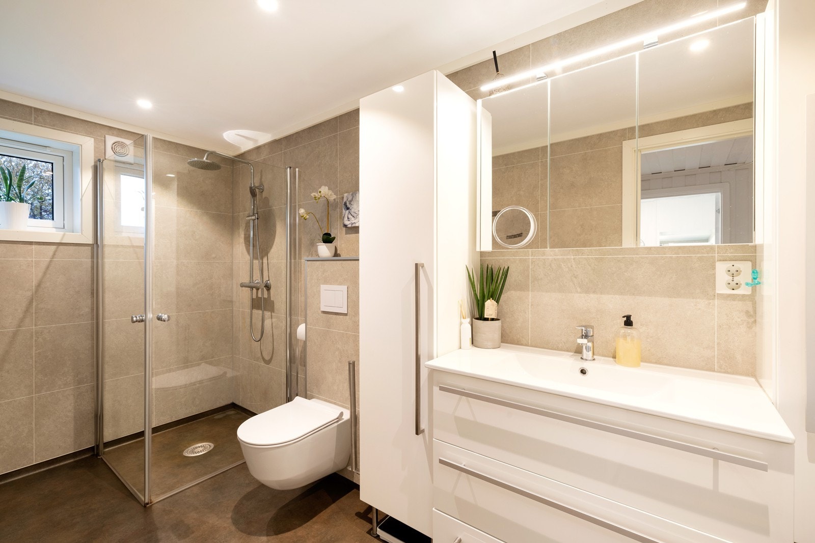 Romslig og innbydende bad med dusjhjørne, servant og vegghengt wc Galleribilde