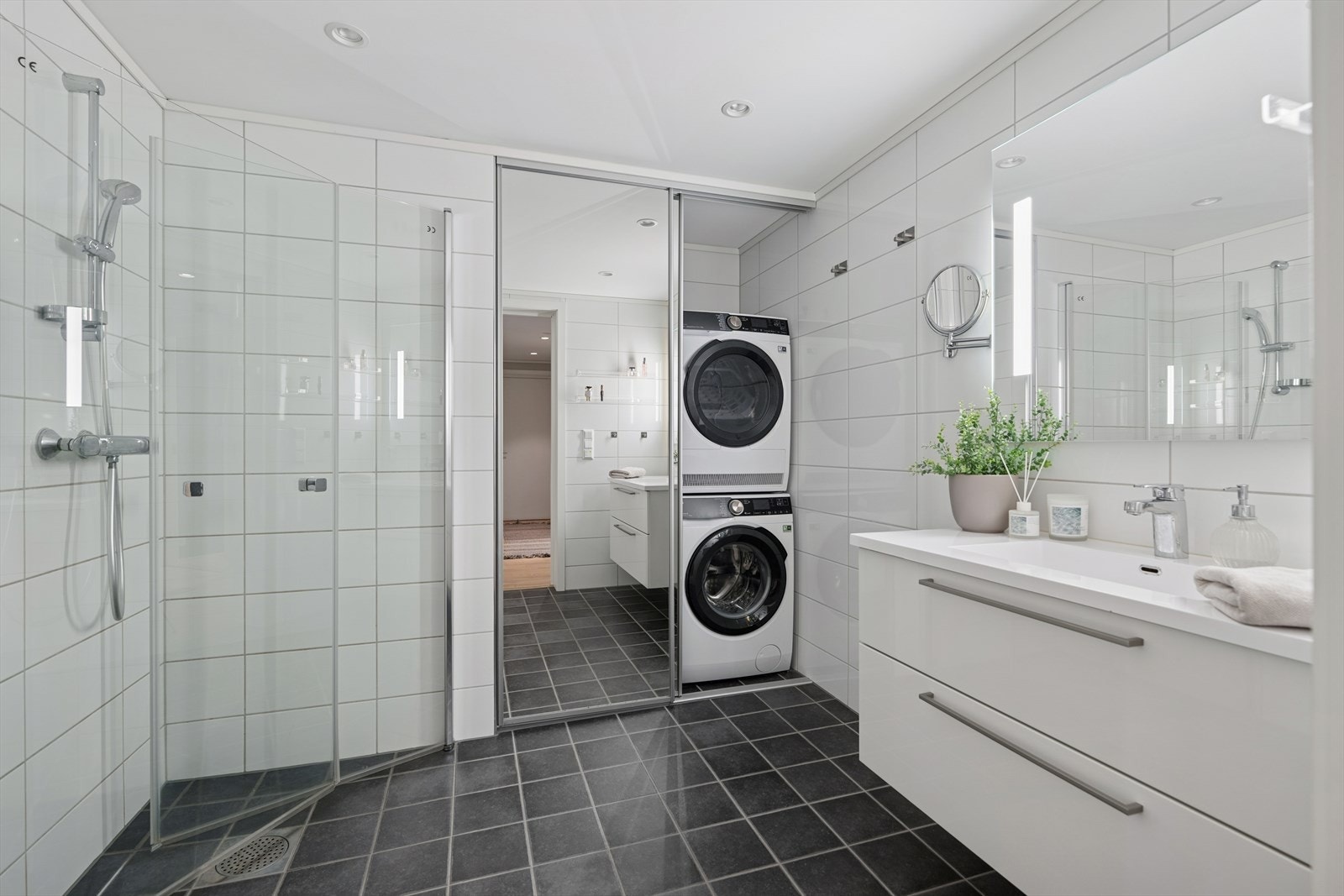 Innbydende helfliset bad/vaskerom med varme i gulv. Baderomsinnredningen er fra HTH og består av heldekkende servant med glatte fronter. På veggen er det montert speil med integrert belysning. Galleribilde