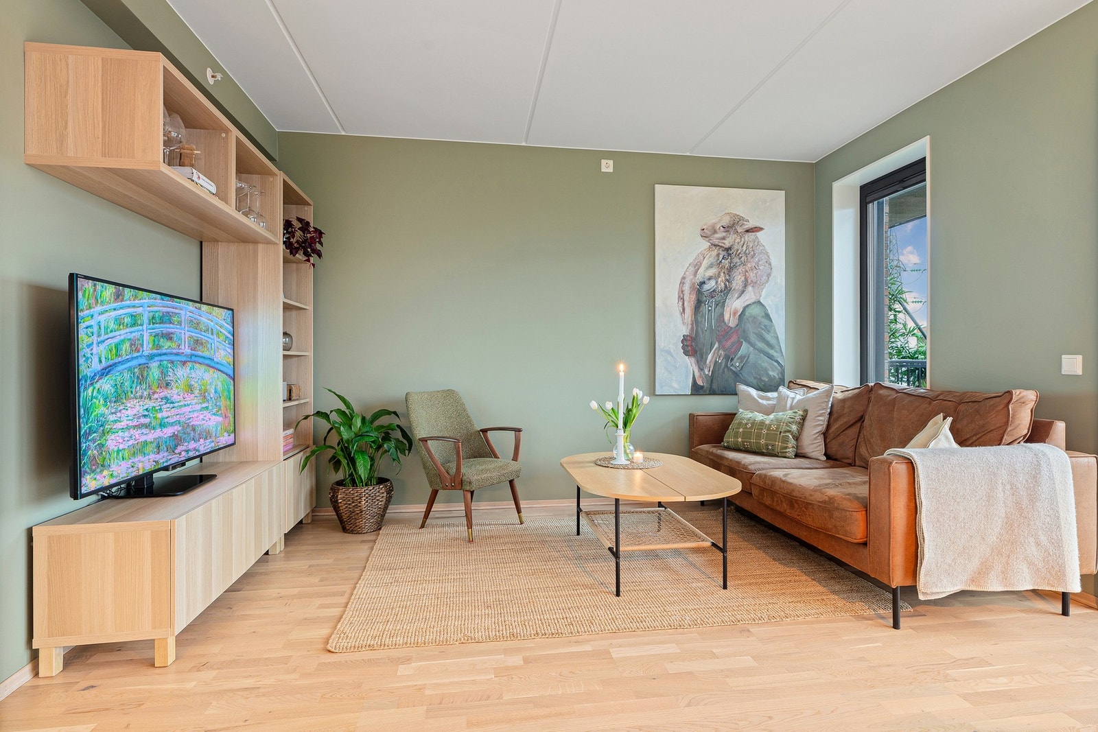 Romslig sofakrok med vannbåren gulvvarme, 3-stavs eikeparkett og store vinduer mot fellesarealer. Galleribilde