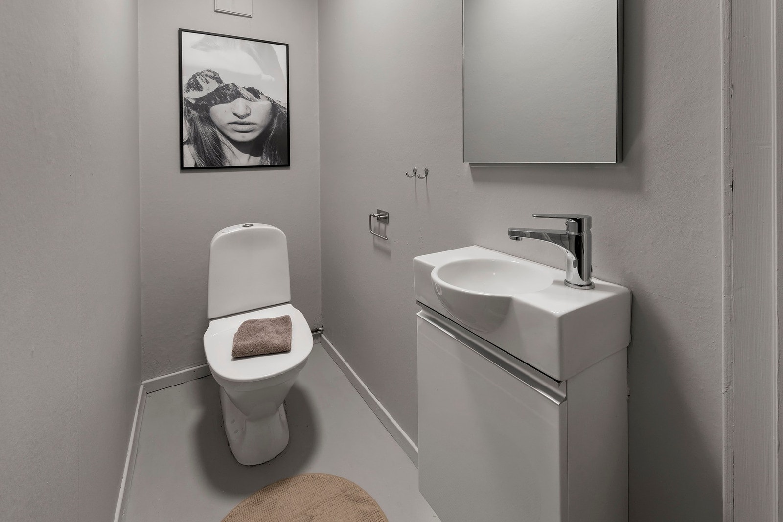 Toalettrom i sokkeletasje har malt vinylbelegg på gulv. Gulvmontert toalett. Servantskap med heldekkende servant Galleribilde