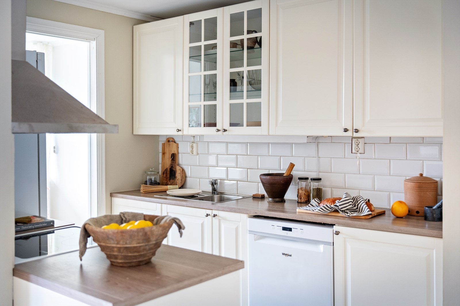 Enkelt kjøkken innredet med benkebereder, kullfiltervifte over stekesonen og opplegg for oppvaskmaskin Galleribilde