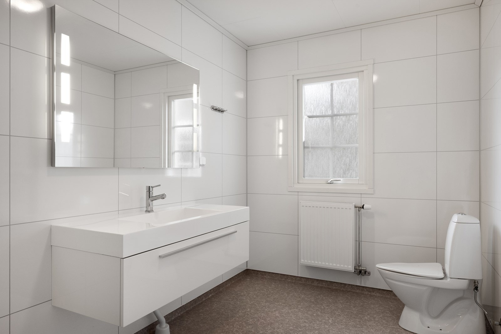 Badet er innredet med toalett, dusj og servant med god plass for oppbevaring. Galleribilde