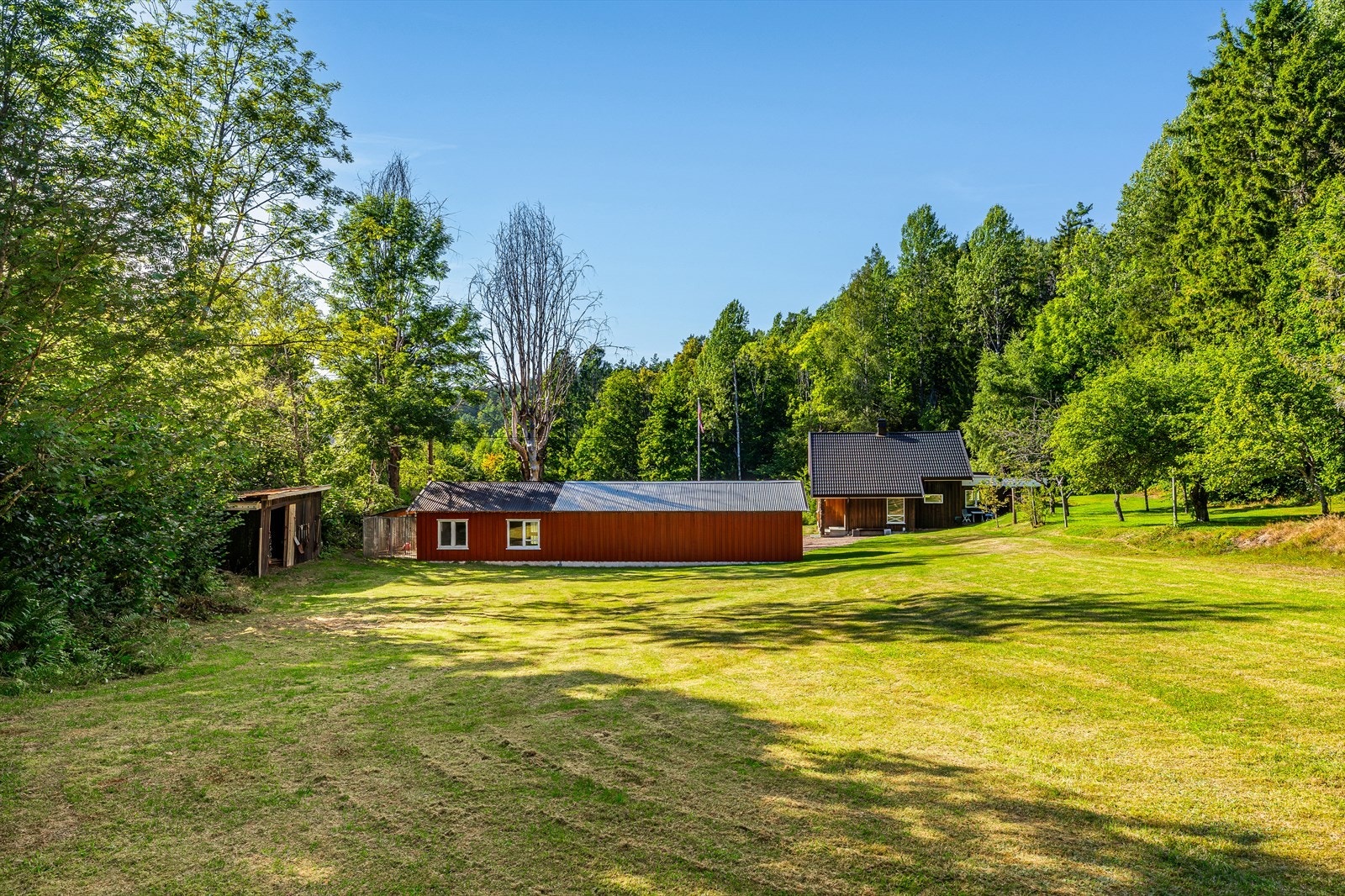 Boligen og garasjen sett fra hagen - god plass og naturlig ramme rundt bebyggelsen. Galleribilde
