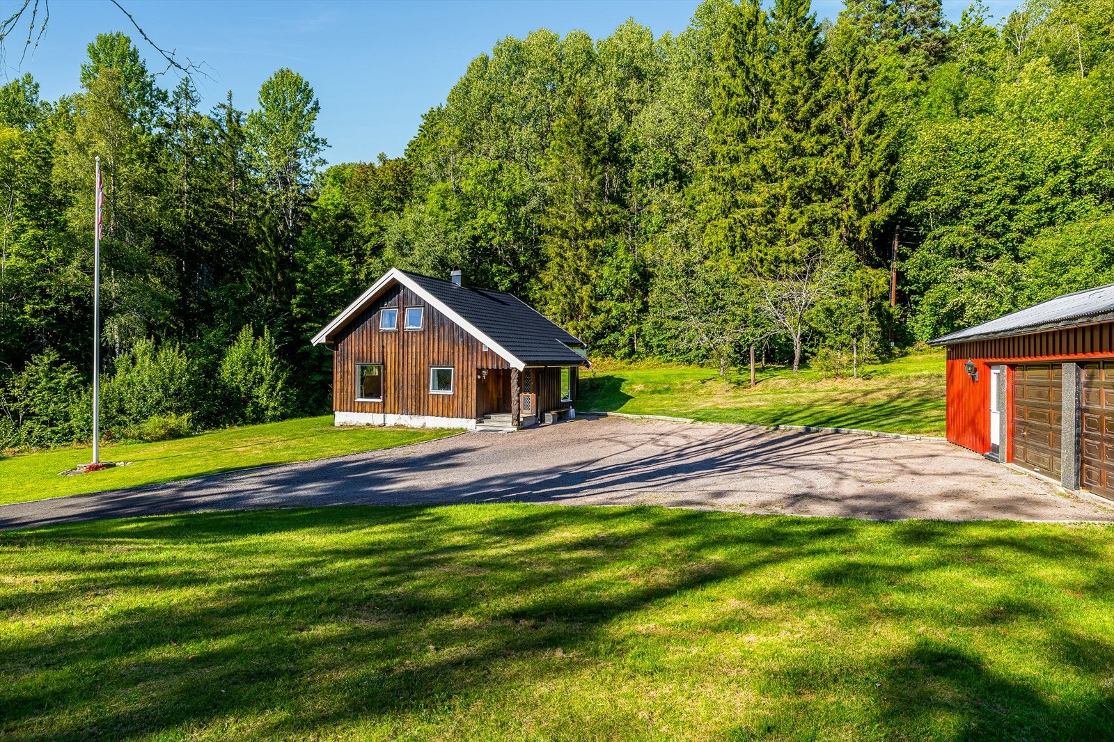Boligen sett fra tunet - omgitt av plenarealer og natur. Galleribilde