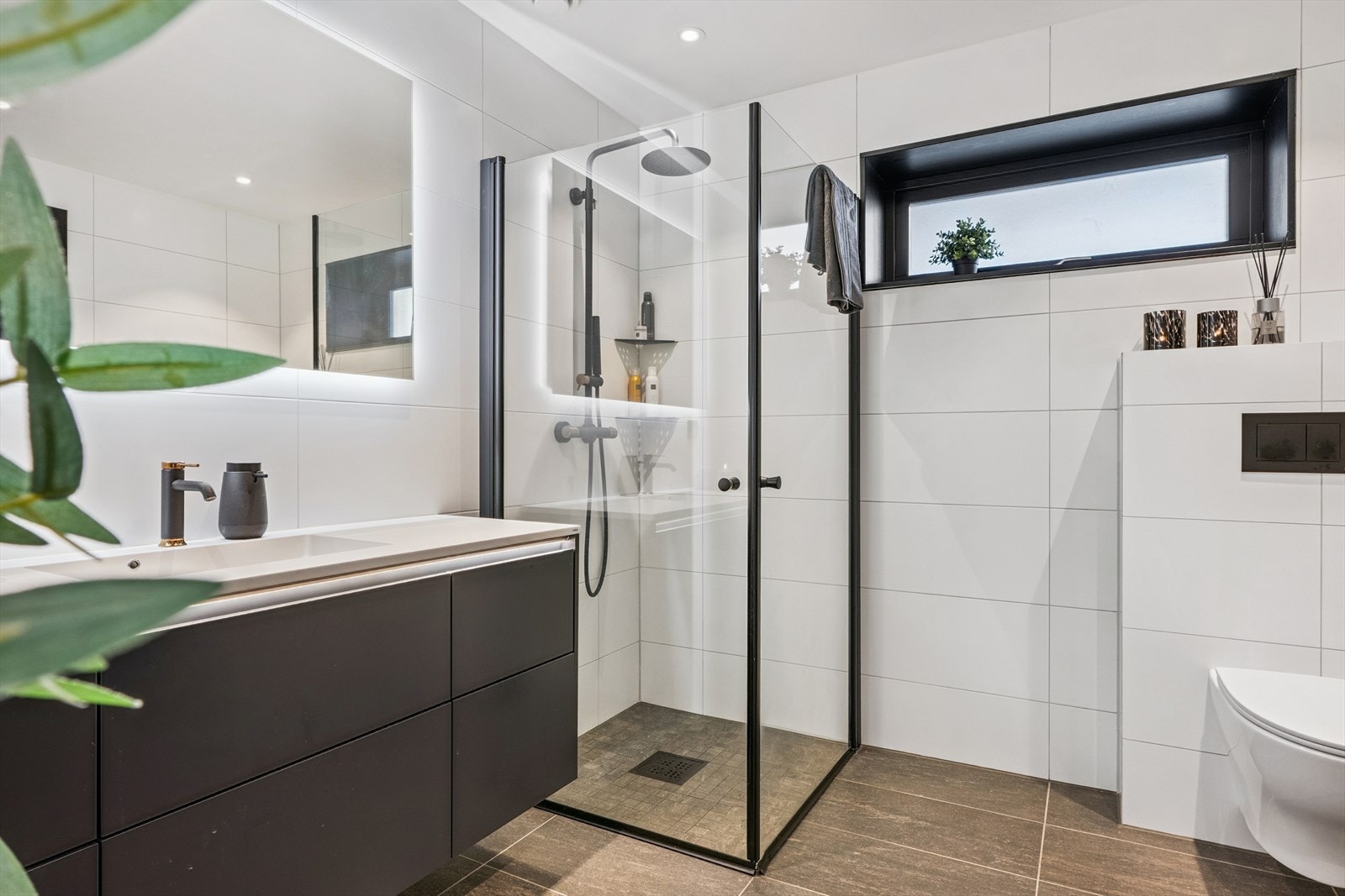 Rommet er utstyrt med innredning med nedfelt servant, vegghengt toalett, dusjvegger og opplegg for vaskemaskin. Galleribilde