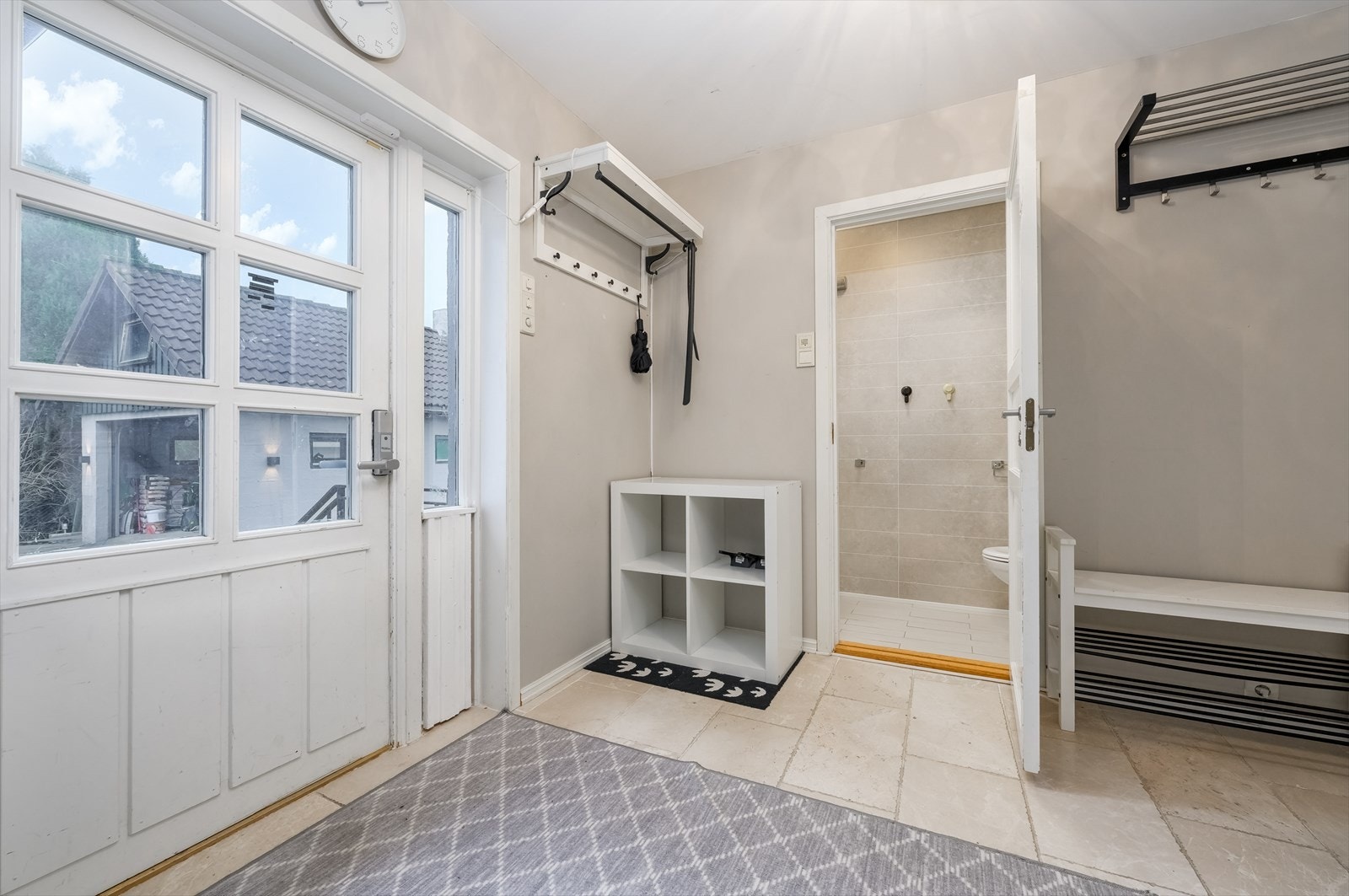 Entreen flislagt gulv og vegger malt i lysegrått. Det er god plass til å henge fra seg yttertøyet, og de lyse gulvflisene Galleribilde