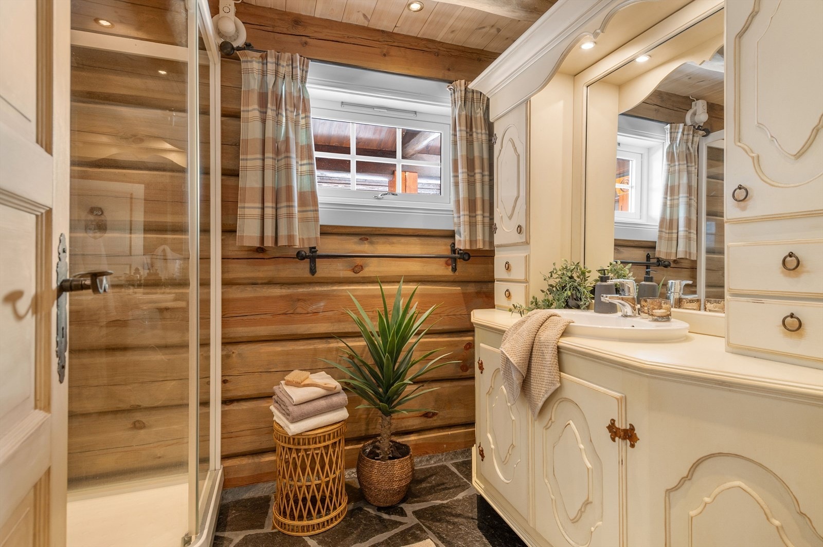 Hytta har to bad - Flislagt gulv og panelte vegger gir badet et robust og naturlig uttrykk. Dusjkabinett og innredning med speilskap gir praktisk funksjonalitet. Galleribilde