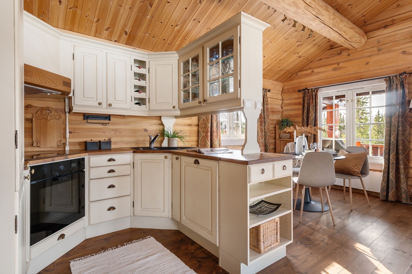 Kjøkkenet har profilerte fronter og en benkeplate i tre som gir et varmt uttrykk. Direkte forbindelse til spiseplassen gir en praktisk løsning for måltider. Galleribilde