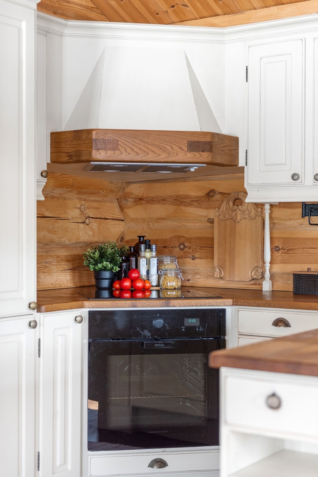 Hvit kjøkkeninnredning med profilerte fronter gir et klassisk preg, og benkeplaten i tre skaper en varm kontrast. Galleribilde