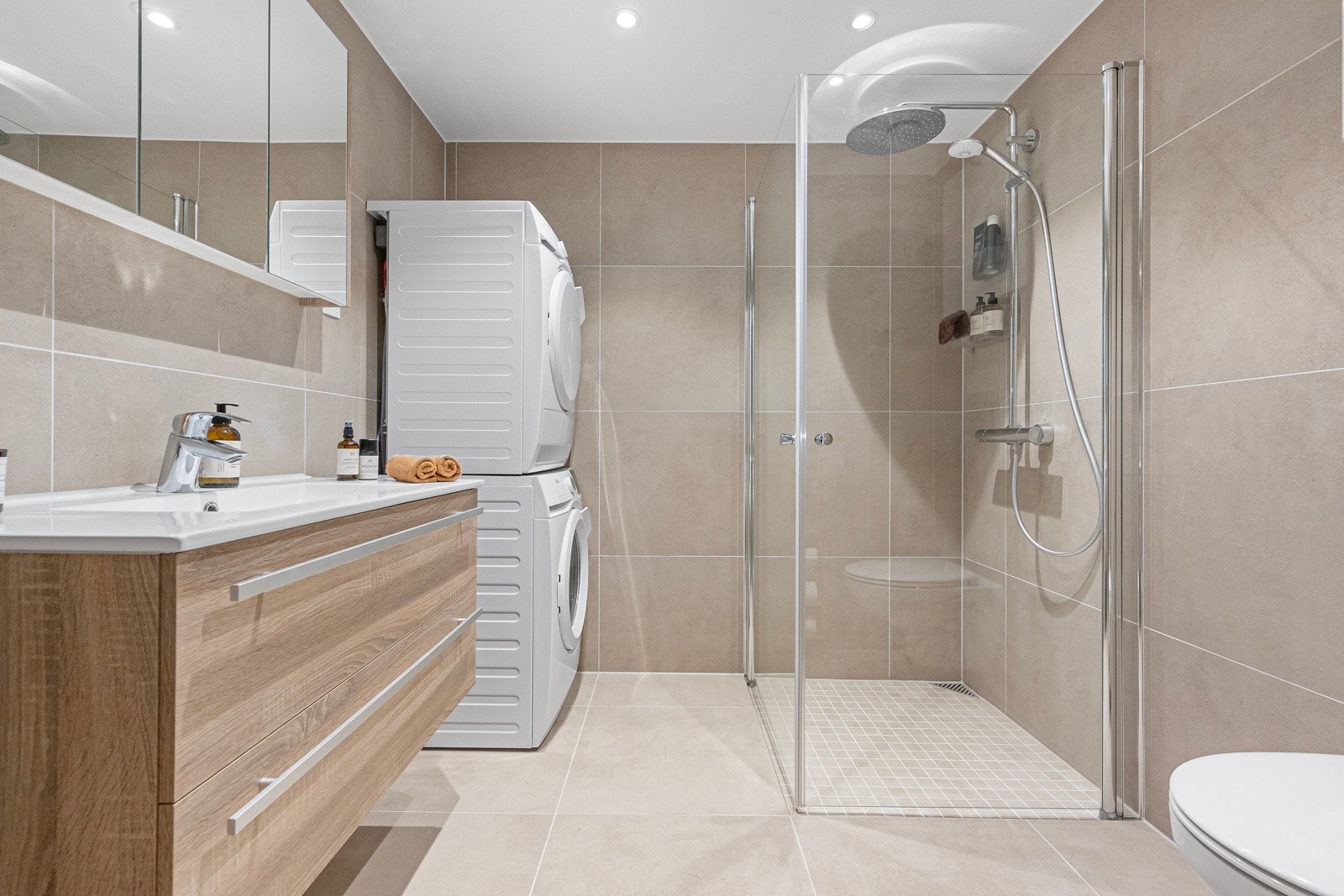 Flislagt bad med dusjvegger og veggmontert wc. Galleribilde