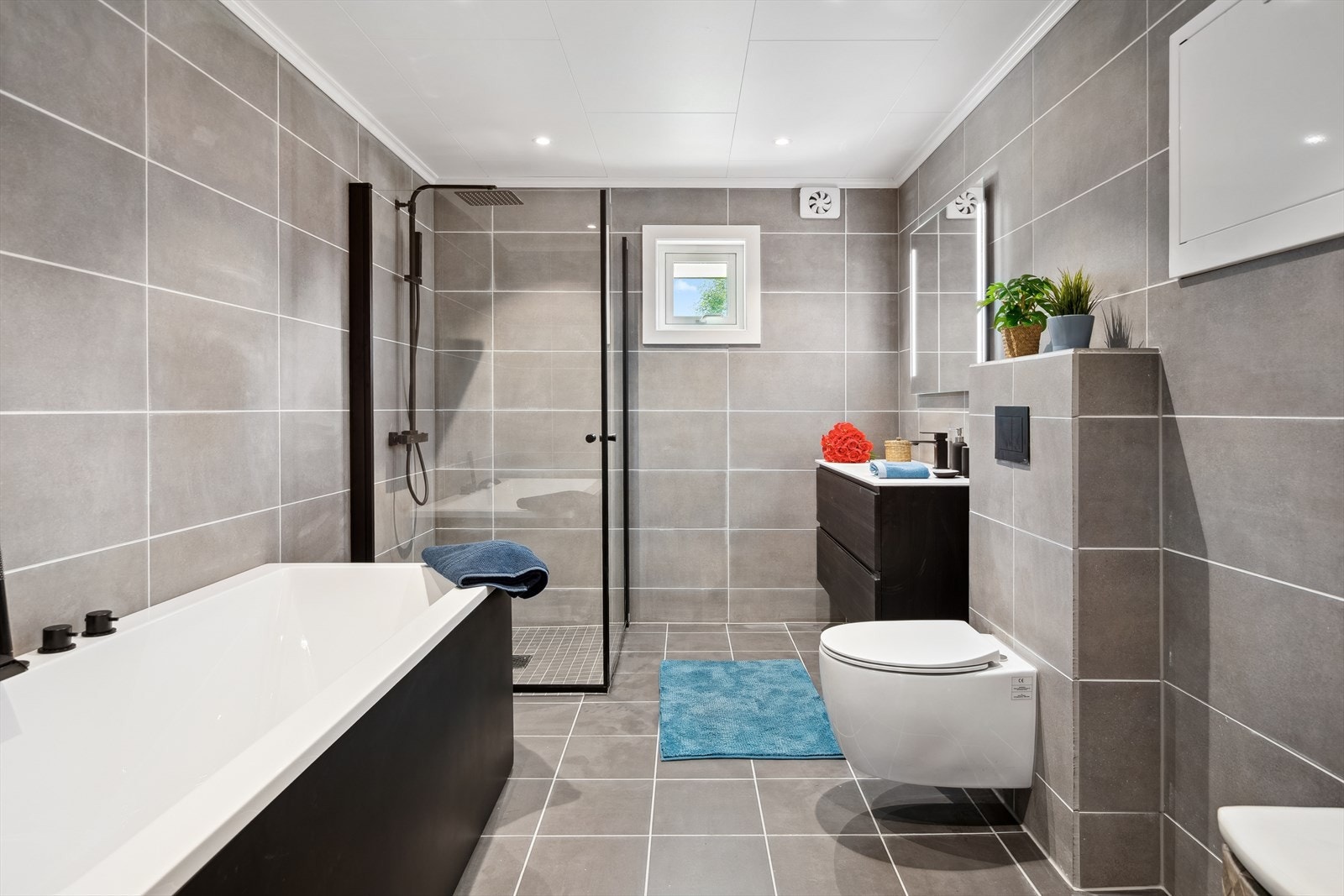 Rommet er innredet med vegghengt toalett, frittstående badekar og dusj med nedsenket dusjsone og innfellbare dører. Galleribilde