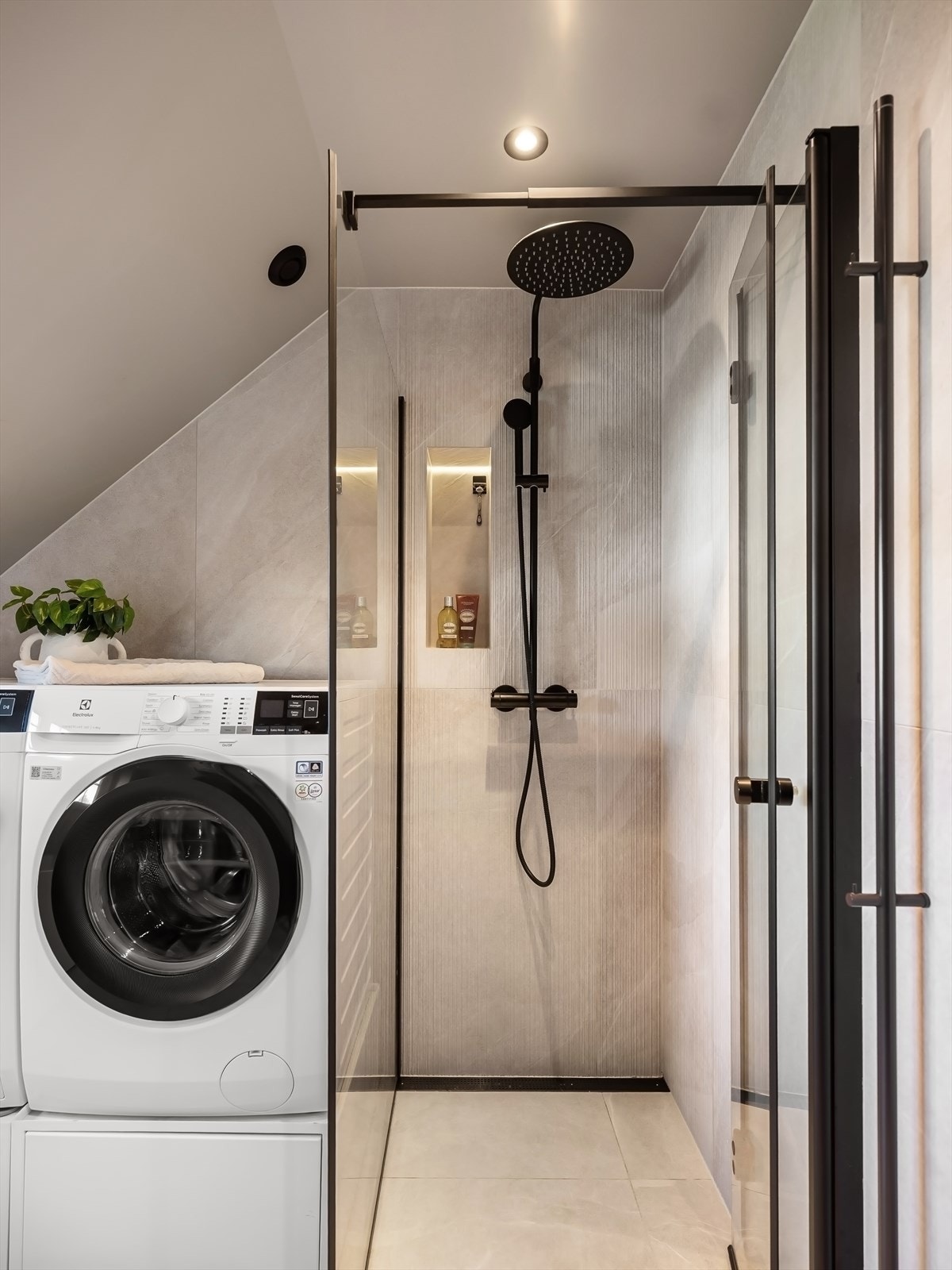 Regnfalldusj, innfelt hylle og innsvingbare dører i glass. Opplegg for vaskemaskin og tørketrommel. Galleribilde