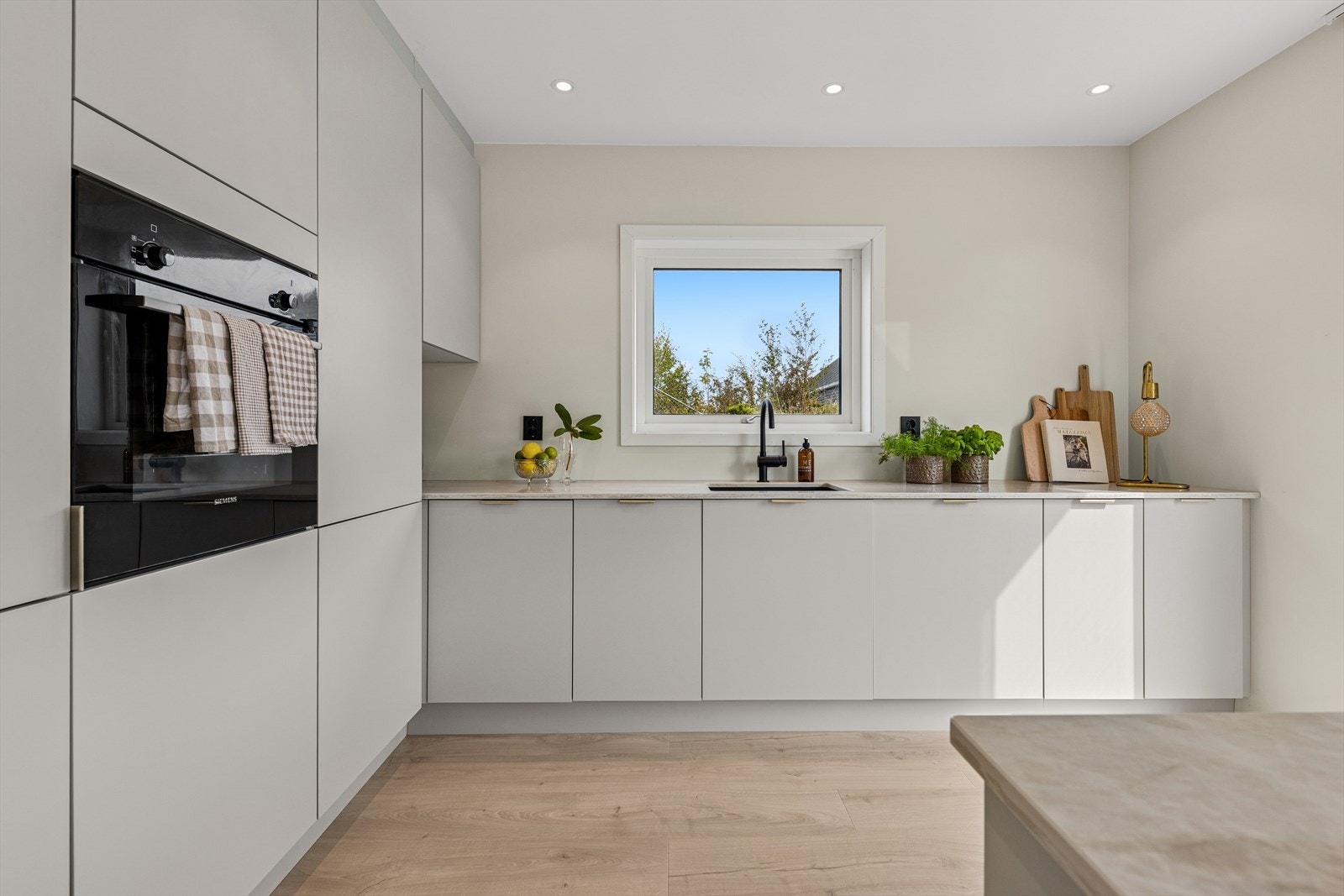 Kjøkkenet er nytt i 2025 og er tidløst innredet med lyse, slette fronter og eksklusiv benkeplate i stein. Et stort og godt kjøkken hvor man har rikelig med skap- og skuffeplass, samt gode arbeidsflater på kjøkkenøy som også fungerer som romdeler. Galleribilde