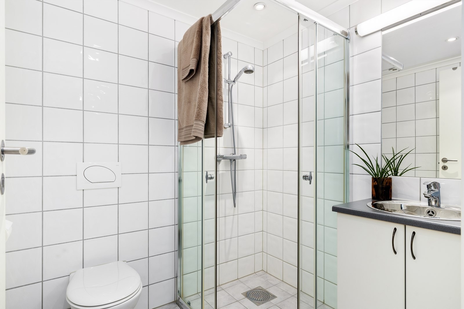 Baderommet er delikat og innbydende, med flislagte overflater og moderne detaljer. Gulvet er flislagt og har behagelige elektriske varmekabler som gir en lun og komfortabel opplevelse.Taket er malt og utstyrt med downlights som gir et godt og jevnt lys. Galleribilde