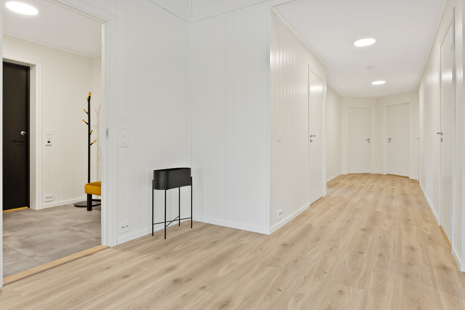 Gangen har laminatgulv og flere dører som gir tilgang til ulike rom i boligen. Galleribilde