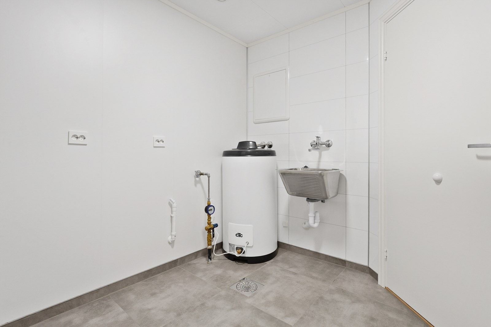 Vaskerommet har flislagt gulv og installert varmtvannsbereder, med praktisk utslagsvask og opplegg for vaskemaskin. Galleribilde