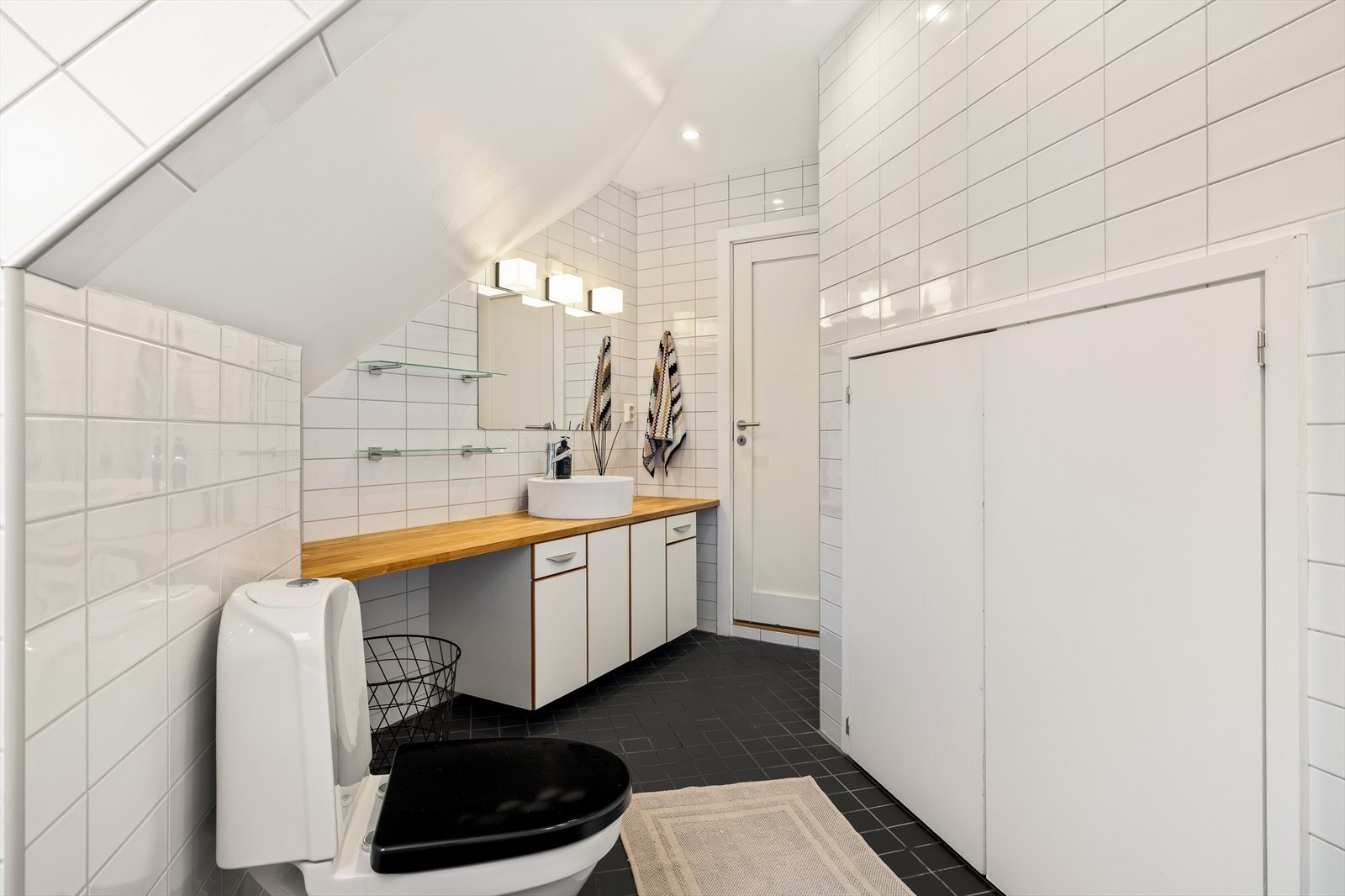 Hovedbadet ligger praktisk tilknyttet gangen og fremstår med klassiske, pene fliser og behagelig gulvvarme. I tillegg skjuler det smarte løsninger som gir både stil og funksjonalitet......... Galleribilde