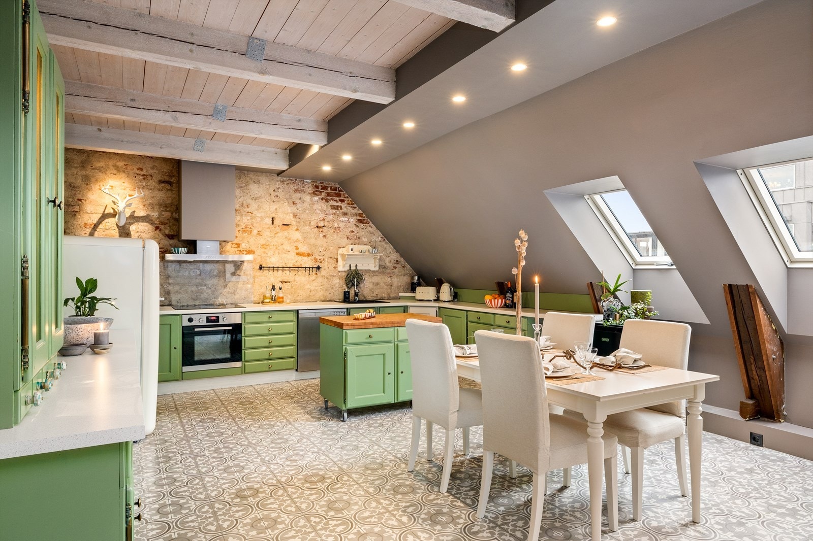 Det særdeles romslige kjøkkenet skiller seg ut med sin elegante grønne farge og bonderomantiske sjarm. Historiske fliser setter prikken over i-en, mens eksponert teglstein og røffe detaljer gir karakter. Moderne, stramme linjer og gjennomtenkt belysning. Galleribilde