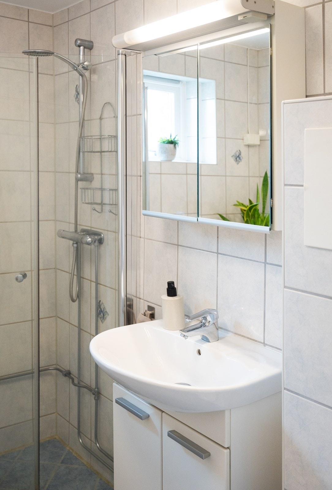 Badet er utstyrt med dusjhjørne, vegghengt toalett, servant og har opplegg for vaskemaskin. Galleribilde