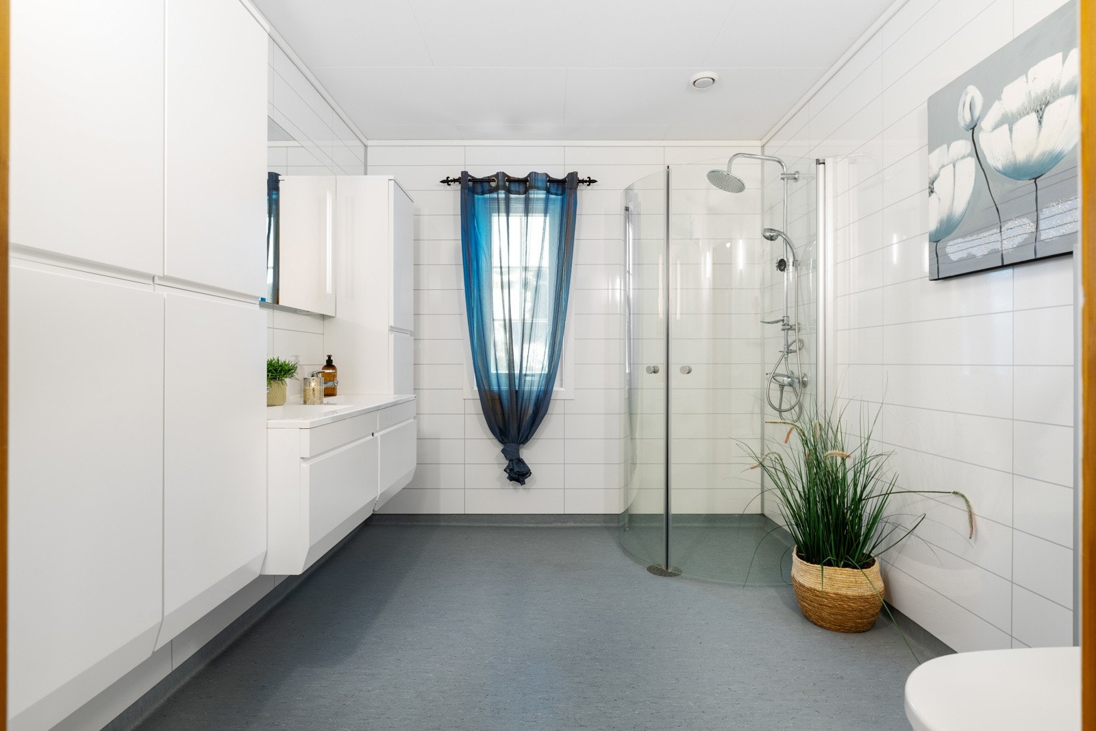 Lyst og romslig baderom med toalett, dusj og servant med underbygg. Galleribilde