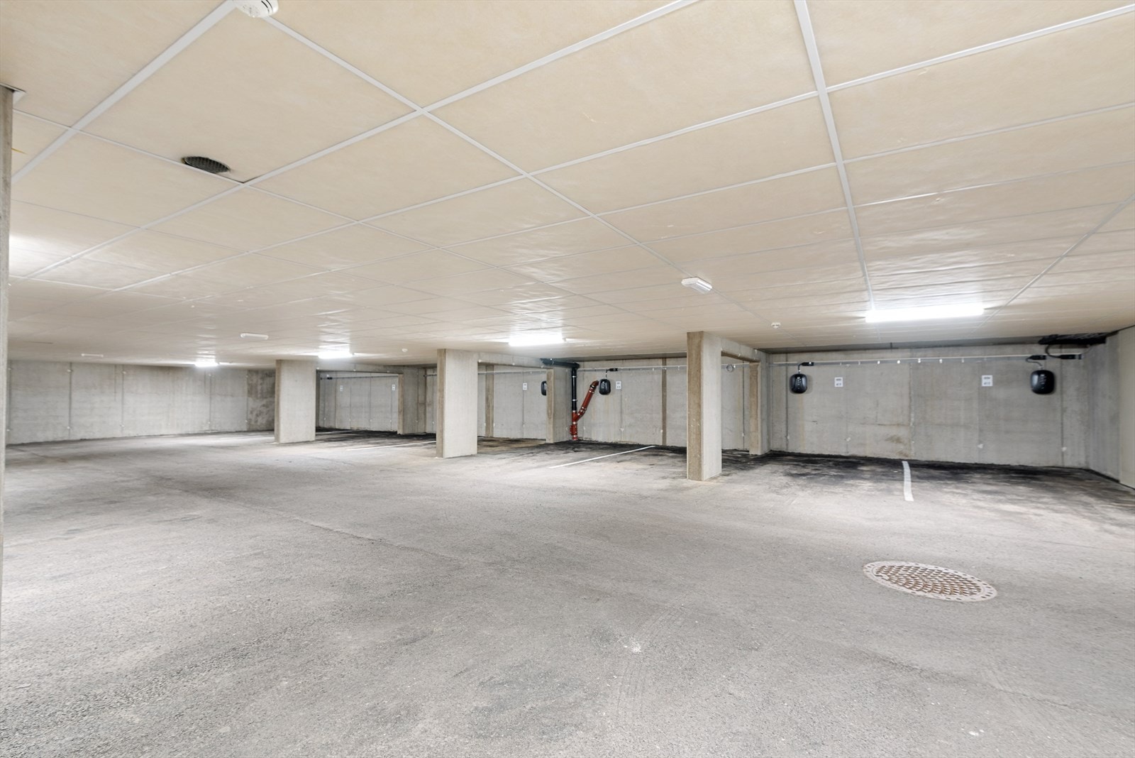 Parkering i garasjekjeller. Det er elbil-lader på parkeringsplassen som tilhører leiligheten. Galleribilde