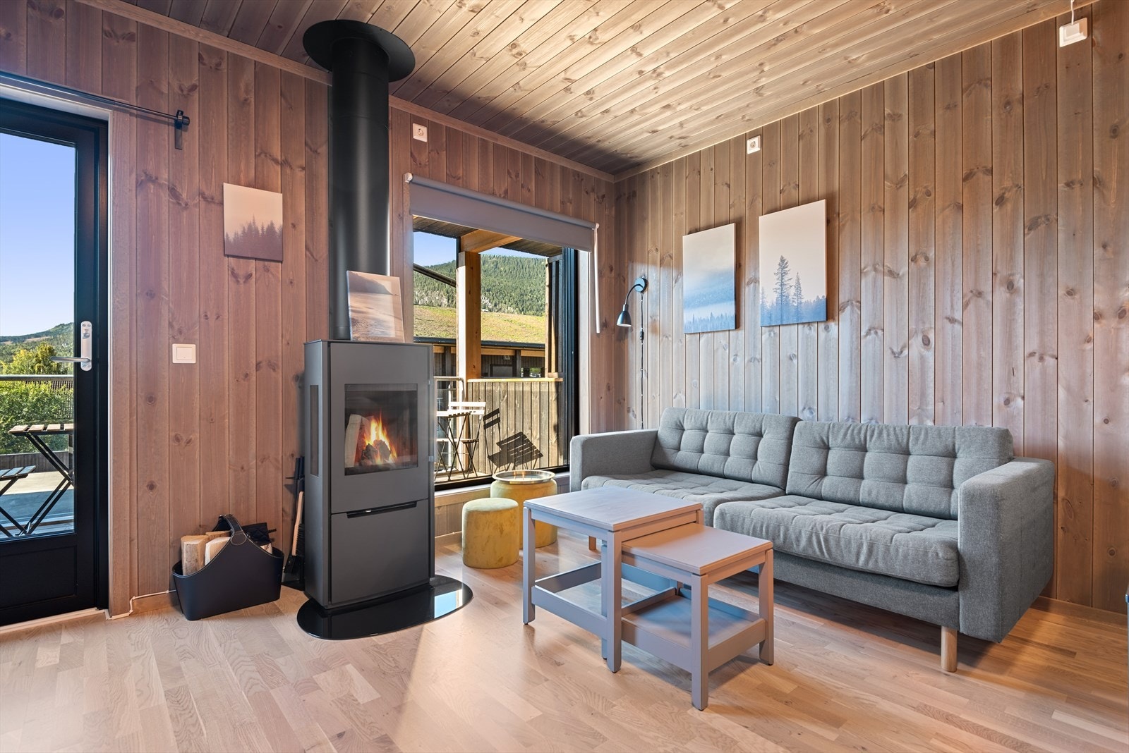 Pen stue med beiset panel på vegger og i tak. Peisovnen varmer godt på kalde vinterkvelder. Galleribilde