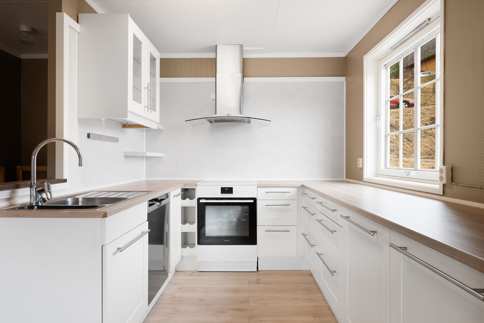 Den lyse, klassiske innredningen fra 2020 har profilerte fronter og benkeplate i laminat. I tillegg ett overskap med glassfront. Galleribilde