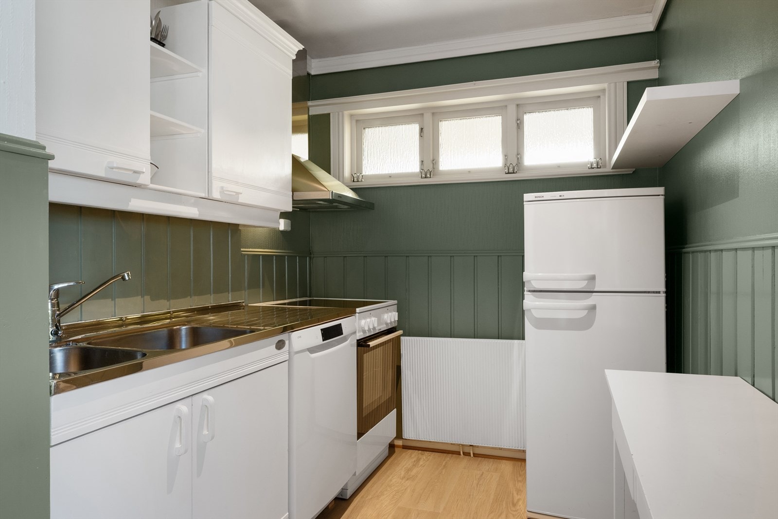 Kjøkkenkroken har lys innredning, frittstående komfyr og kjøleskap, samt opplegg for vaskemaskin. Galleribilde